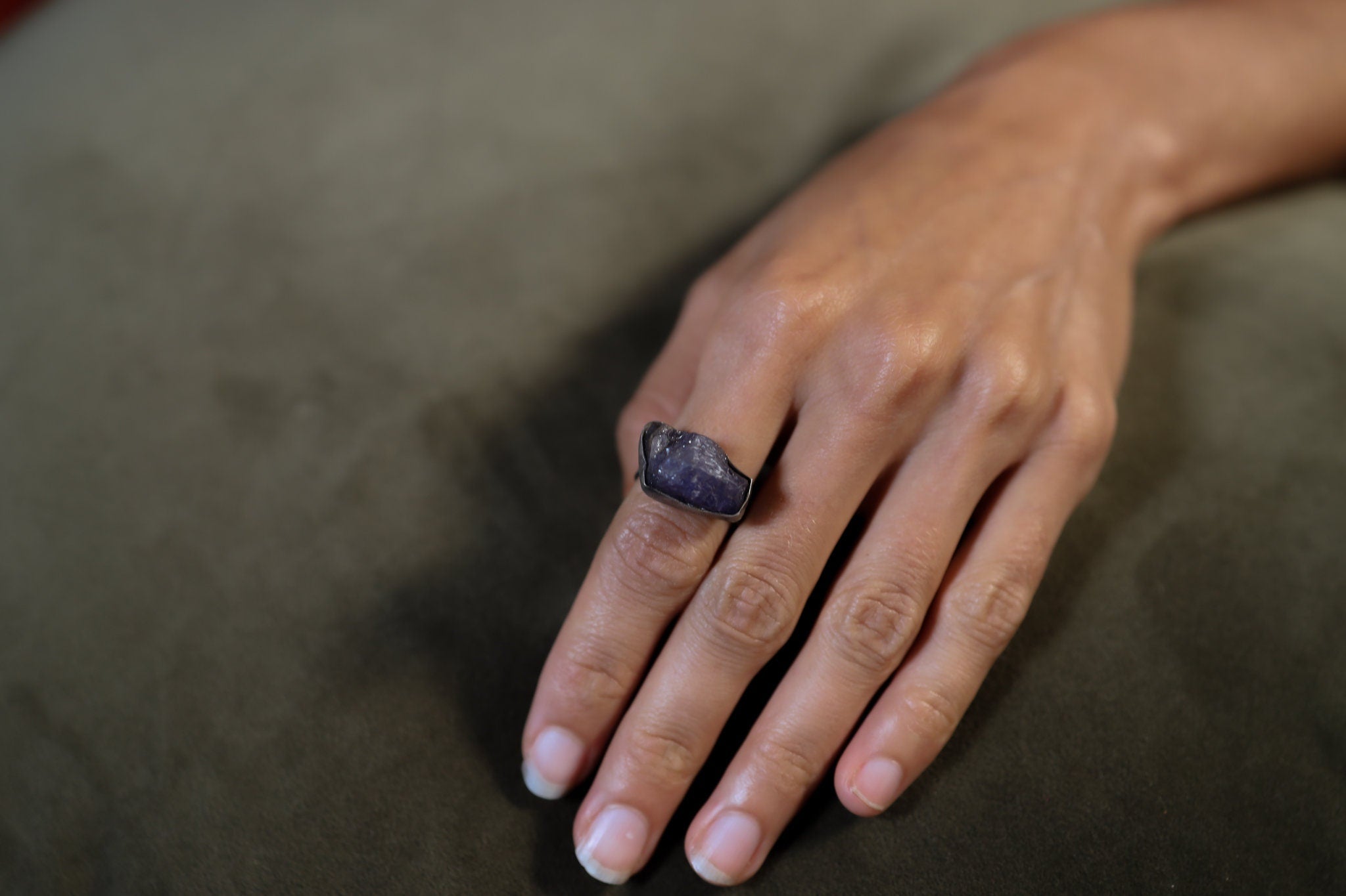 Raw Tanzanite ring shown worn on the hand as a blue-violet December birthstone ring in handmade sterling silver.
