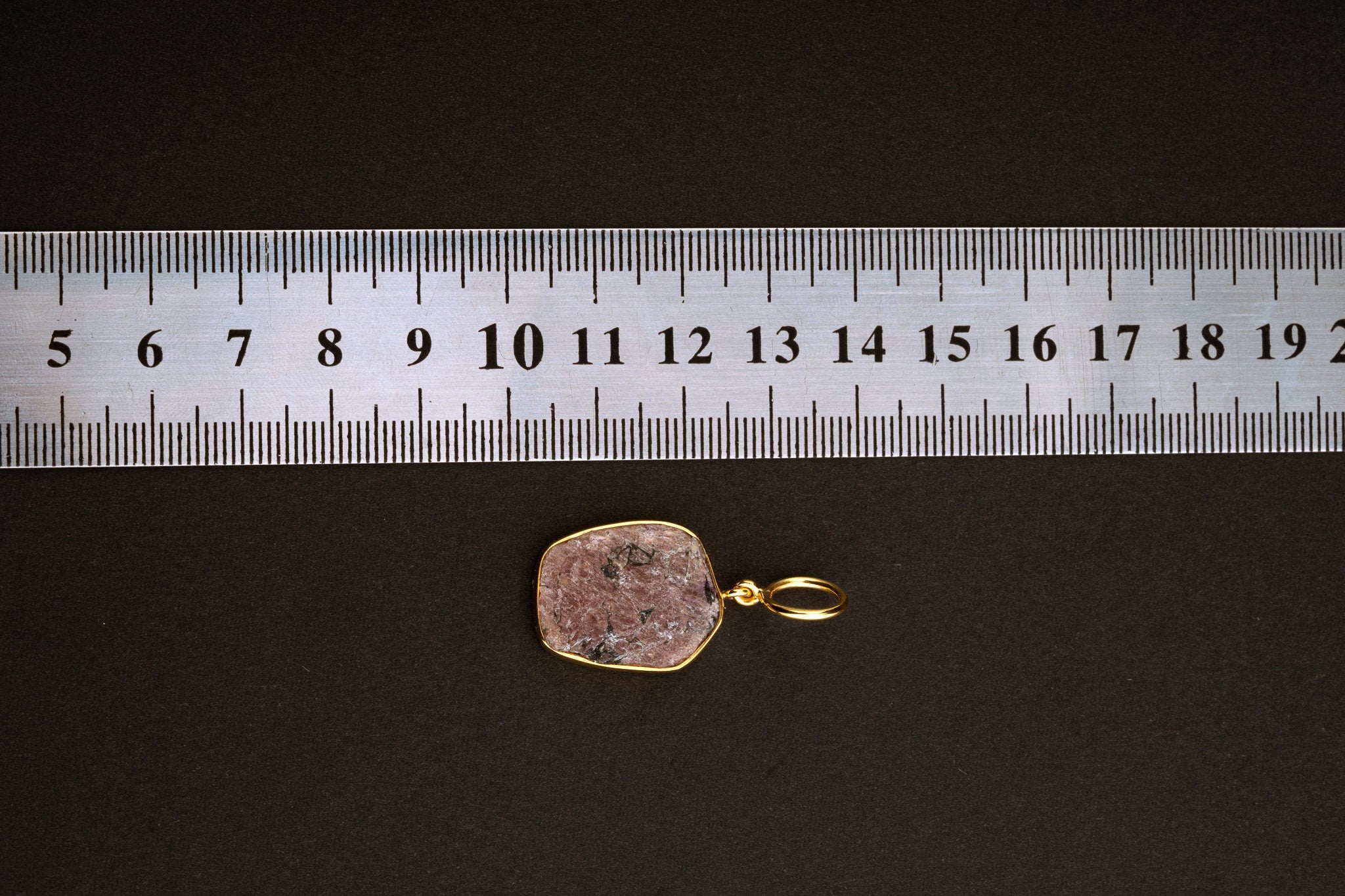 The ruler image appears clear enough to estimate the pendant at approximately 3 to 3.5 cm total length including bail. The product appears to be a single raw Ruby pendant rather than a double-stone version or collection listing.
