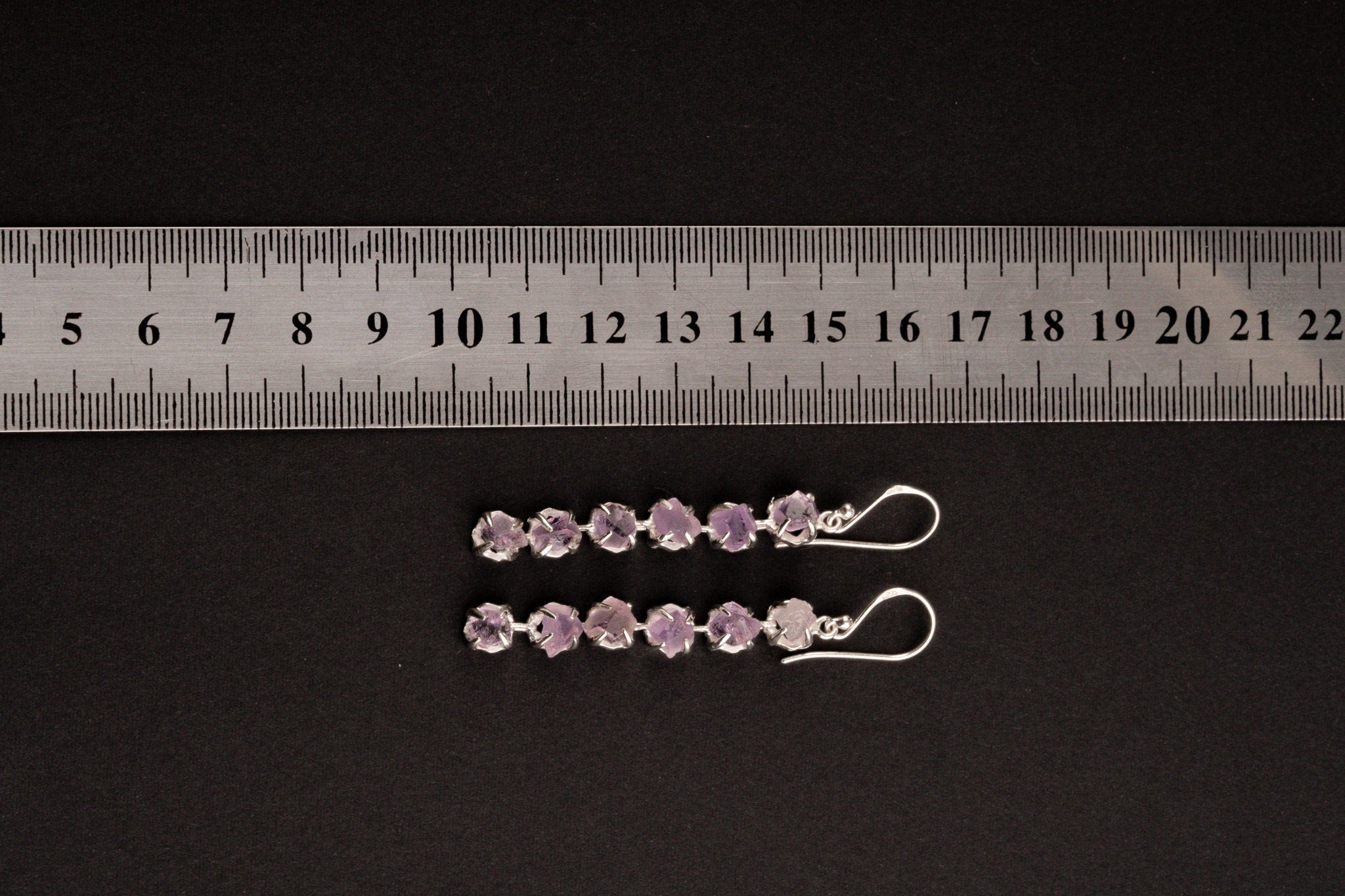 Raw Amethyst dangle earring shown beside a ruler for scale, with six linked stones and sterling silver fittings.