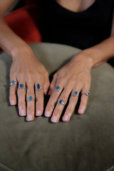 Raw Blue Apatite Ring shown worn on hand with rounded hammered sterling silver band and vivid blue crystal.