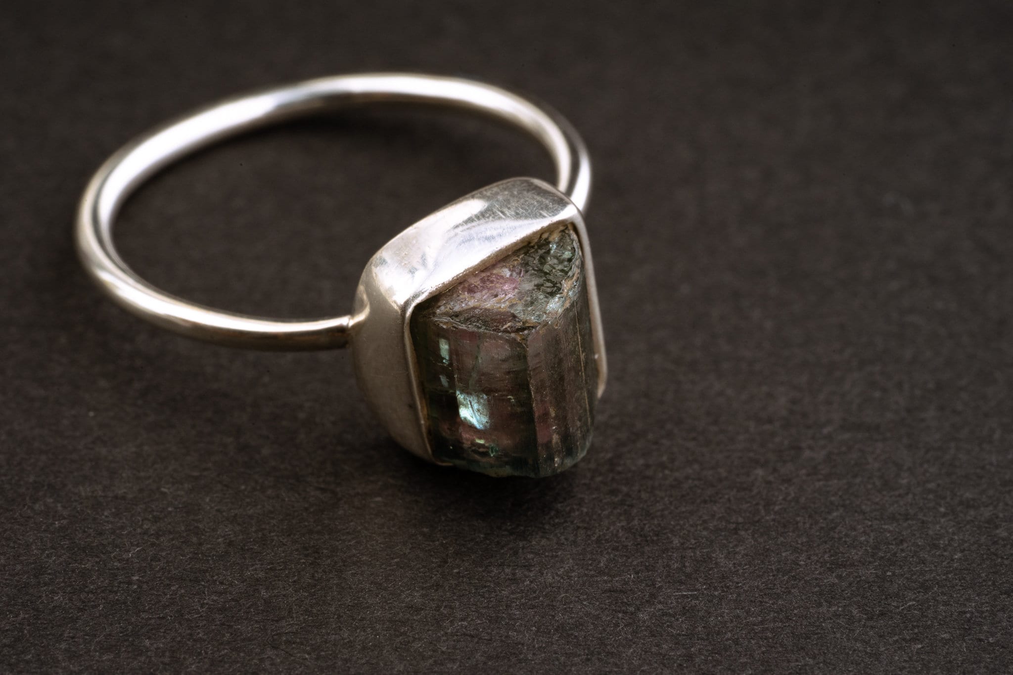 Side view of rough Watermelon Tourmaline ring showing the raised raw stone, revealing bezel setting, and fine silver band.
