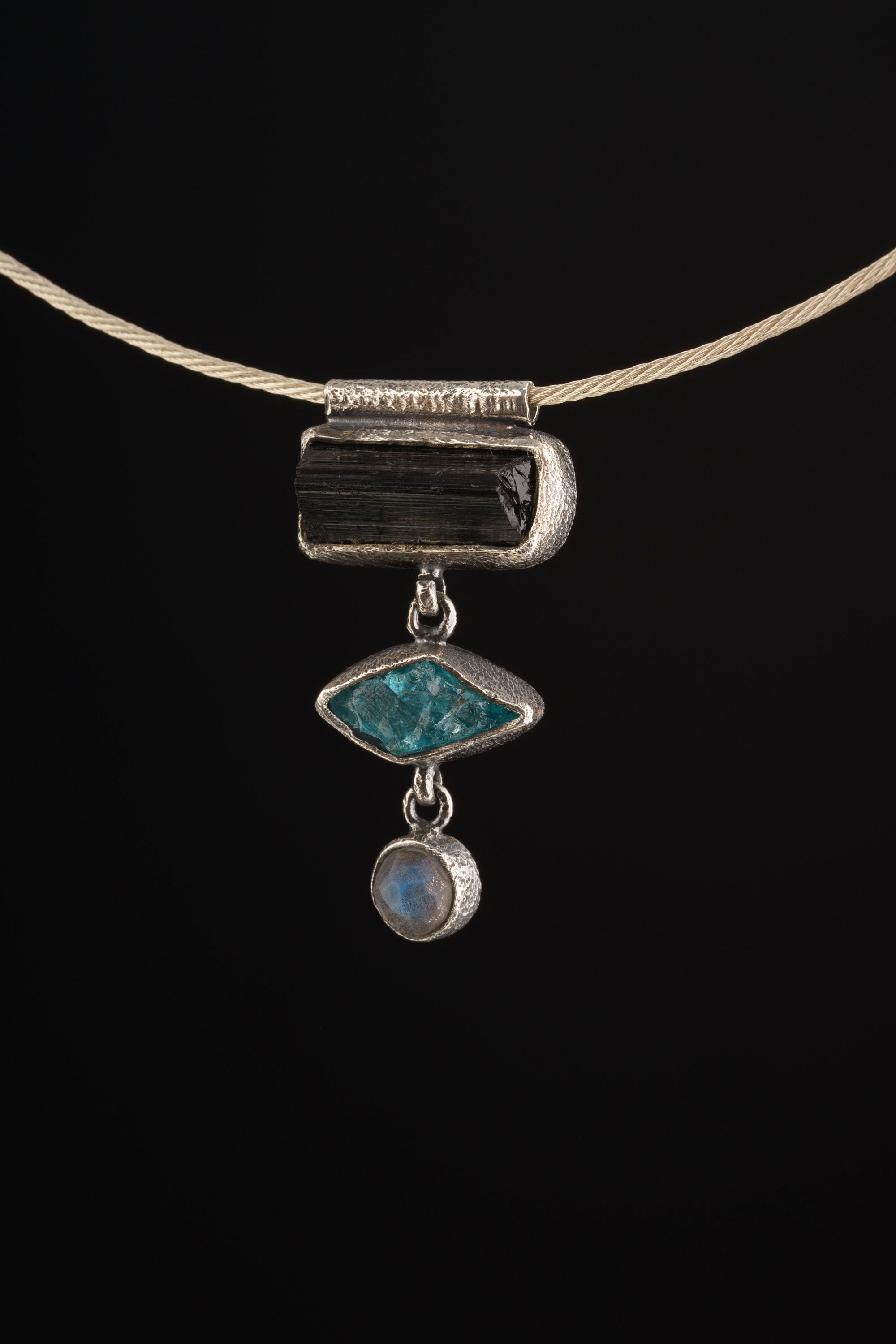 Grounding Vision Stack Pendant shown worn on a model, with oxidized silver and three vertical gemstones.