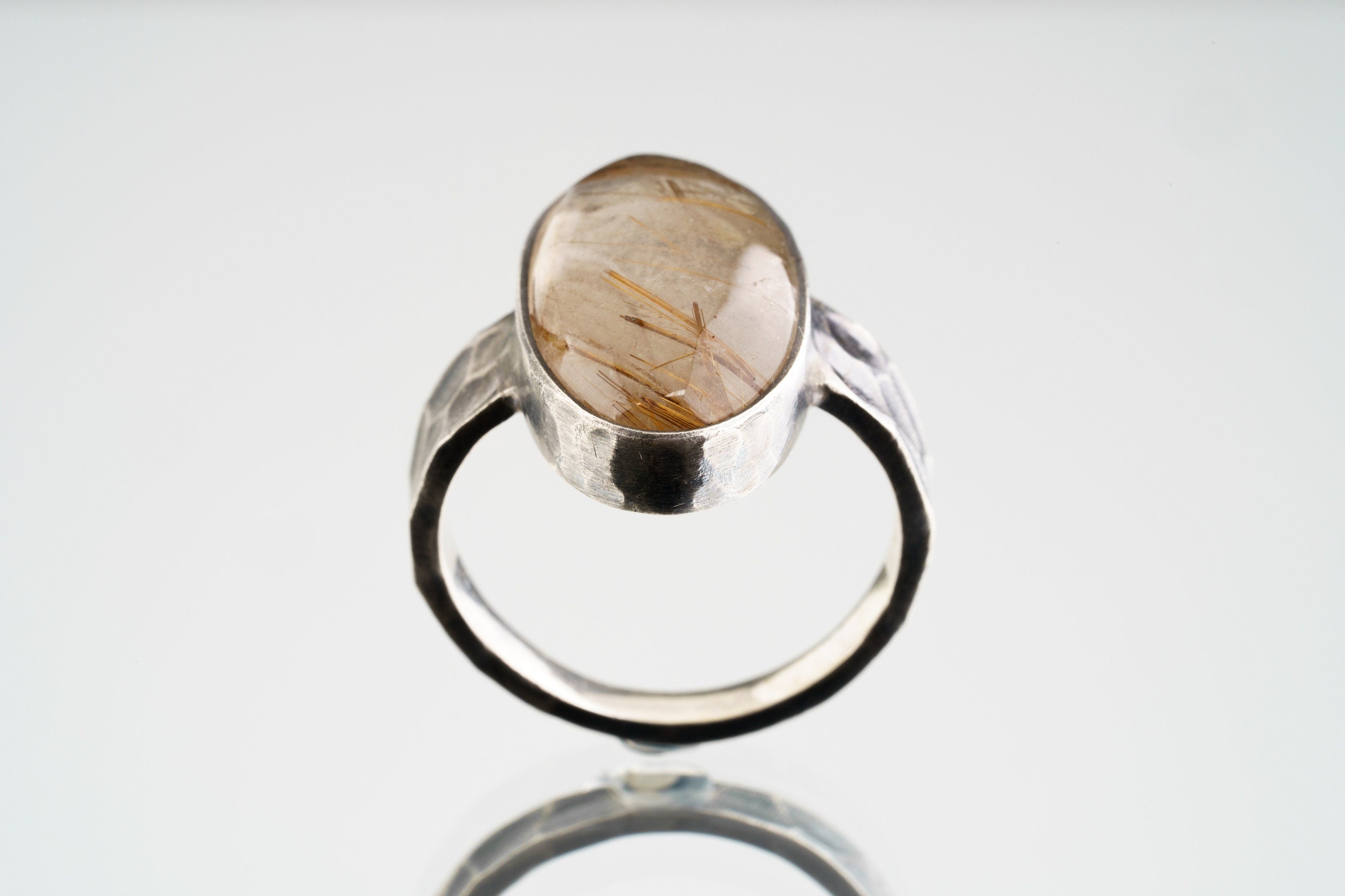 Front view of Rutilated Quartz oxidized silver ring showing oval crystal form and rugged hammered band texture.