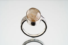 Front view of Rutilated Quartz oxidized silver ring showing oval crystal form and rugged hammered band texture.