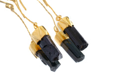 Close-up of handmade Black Tourmaline earrings showing raw black crystal texture and warm gold-plated silver fittings.