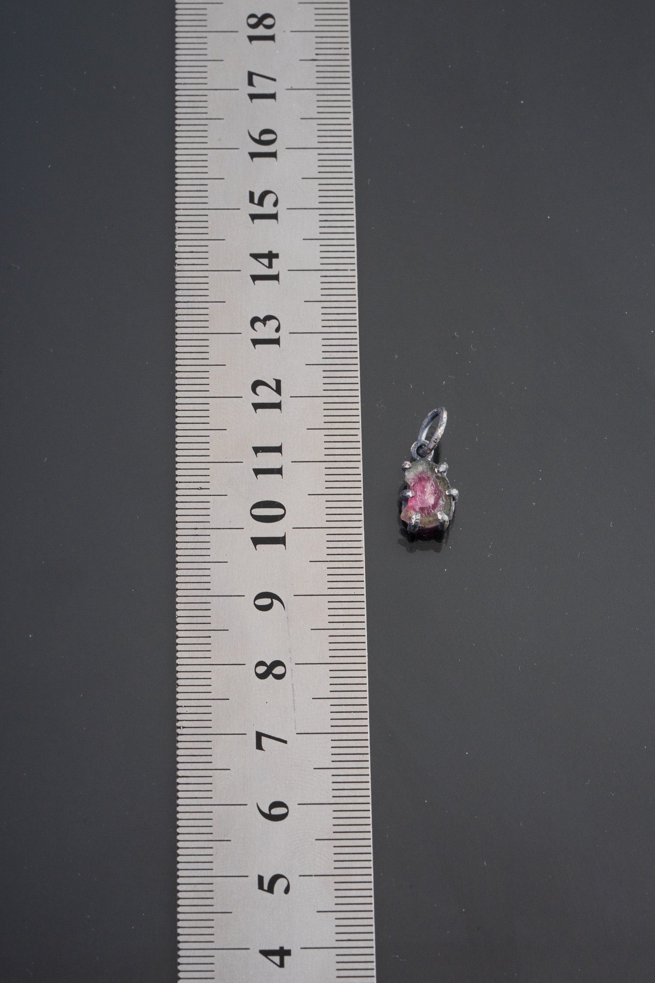 Watermelon Tourmaline pendant shown beside ruler for scale 1.5cm with pink-green crystal in oxidized silver claw setting.