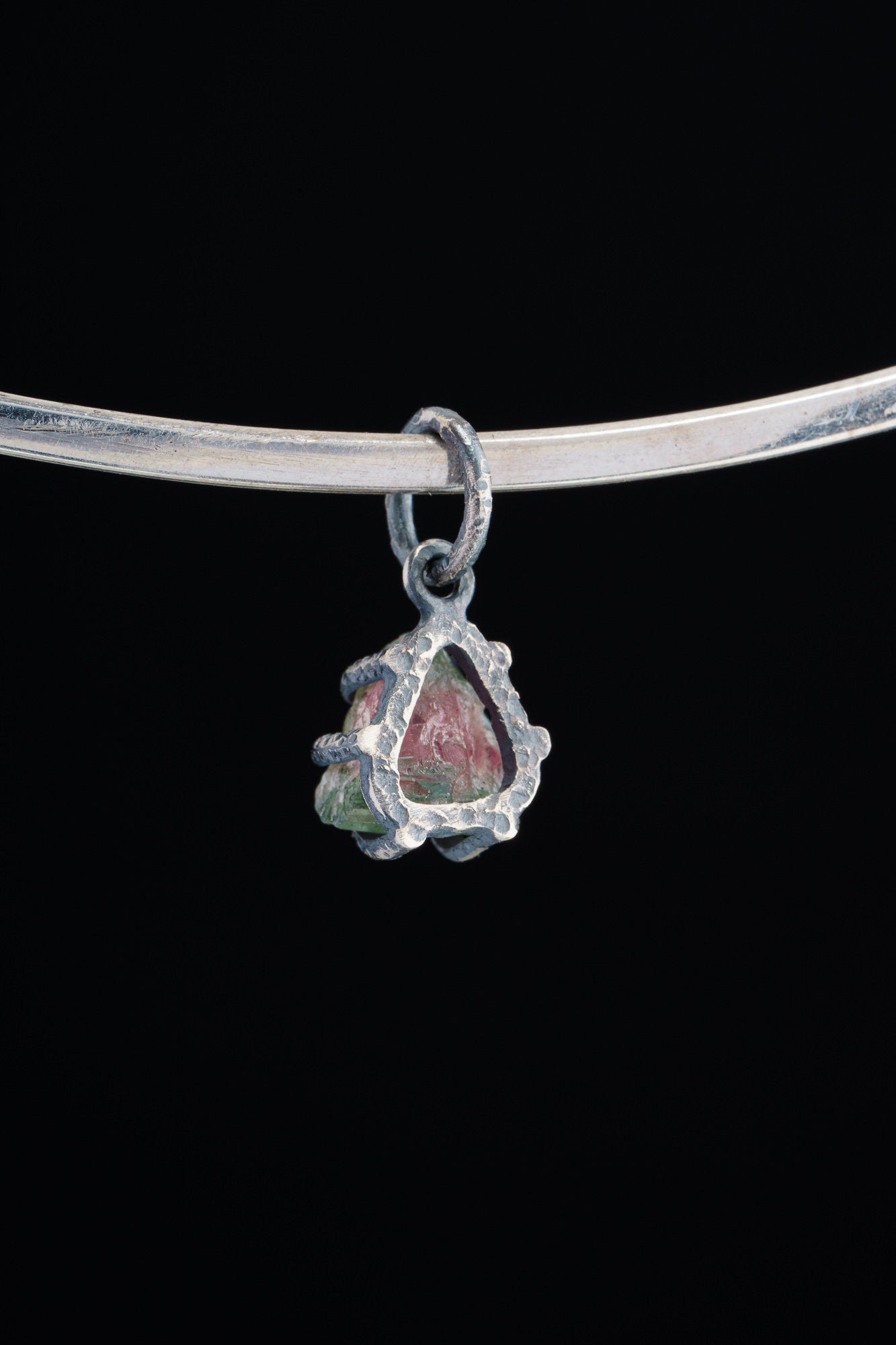 Watermelon Tourmaline Claw Pendant shown worn on black background with handmade oxidized sterling silver setting.