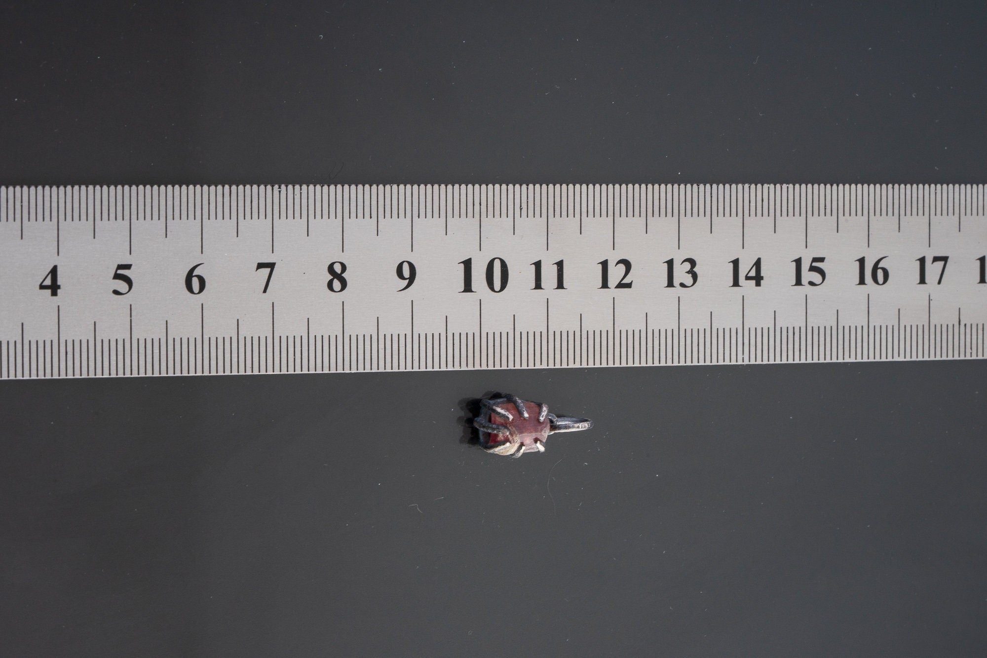 Pink Tourmaline Rubellite pendant shown beside ruler for scale 1.5cm with rose-pink crystal in oxidized silver claw setting.