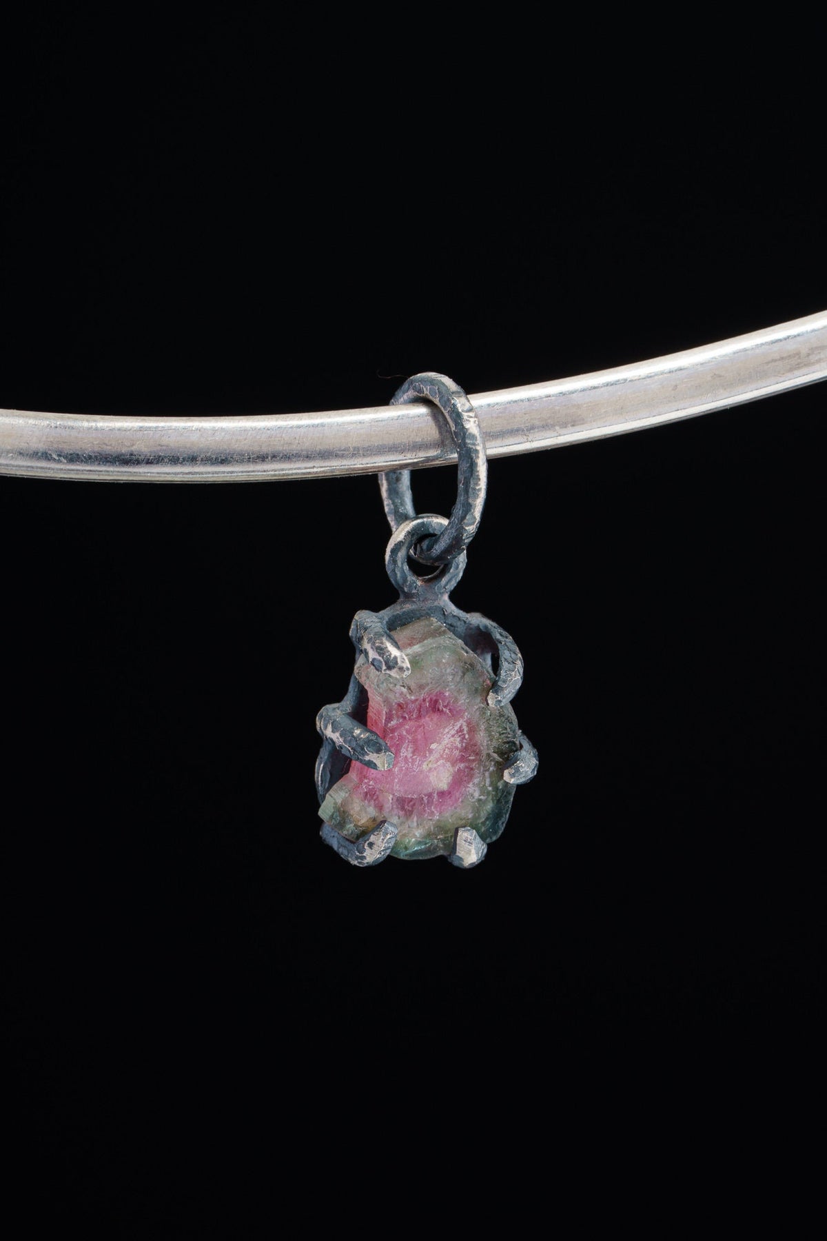 Watermelon Tourmaline Claw Pendant on black background with oxidized sterling silver and natural pink-green crystal.