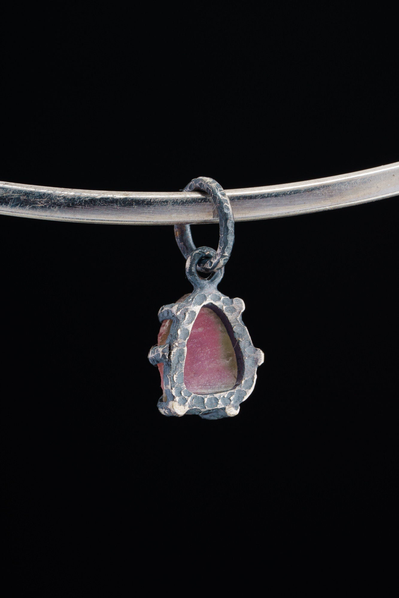 Watermelon Tourmaline Claw Pendant shown worn on black background with handmade oxidized sterling silver setting.