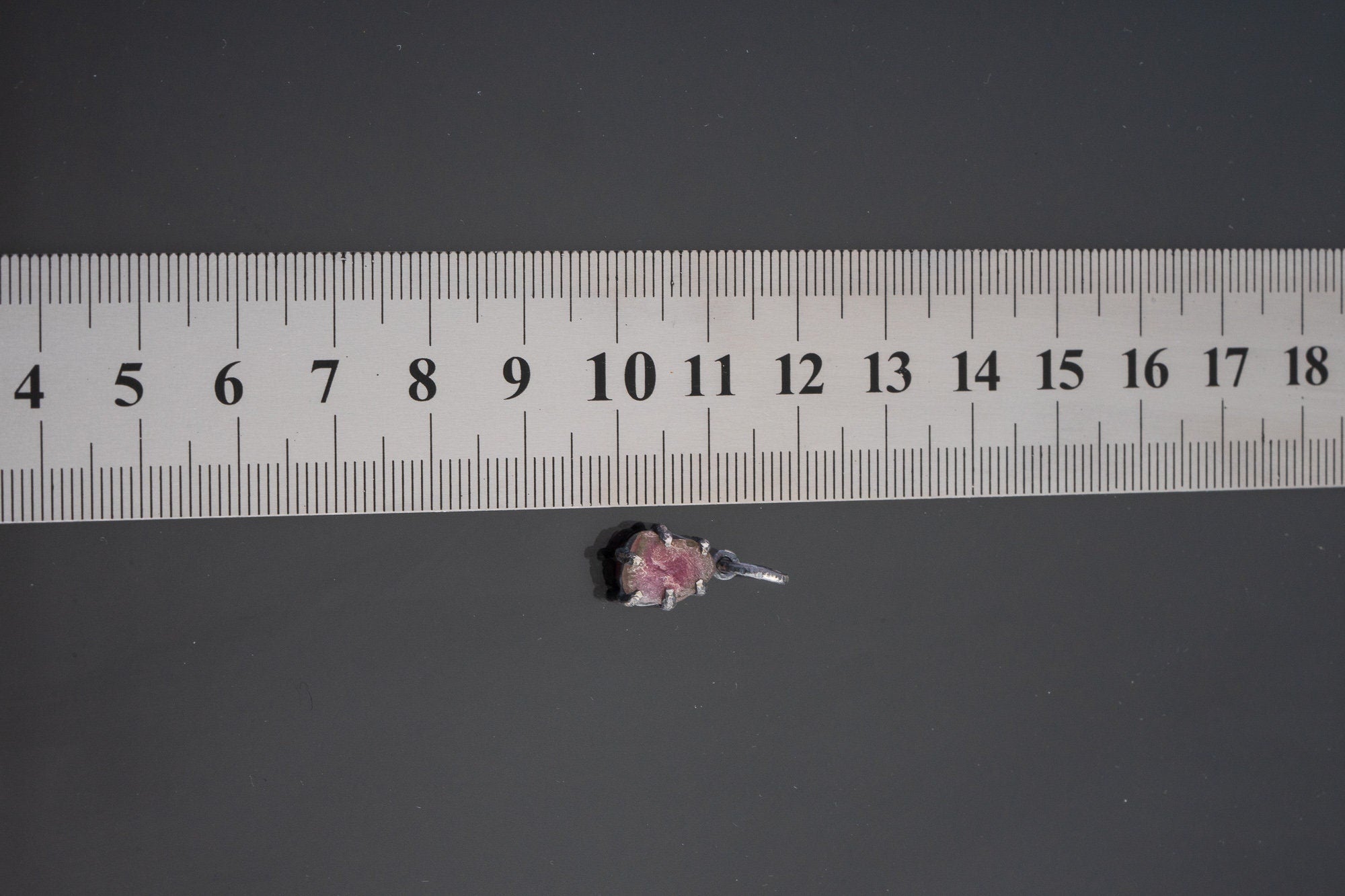 Watermelon Tourmaline pendant shown beside ruler for scale with pink-green crystal in oxidized silver claw setting.