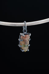 Watermelon Tourmaline Claw Pendant on black background with oxidized sterling silver setting and pink-green gemstone.