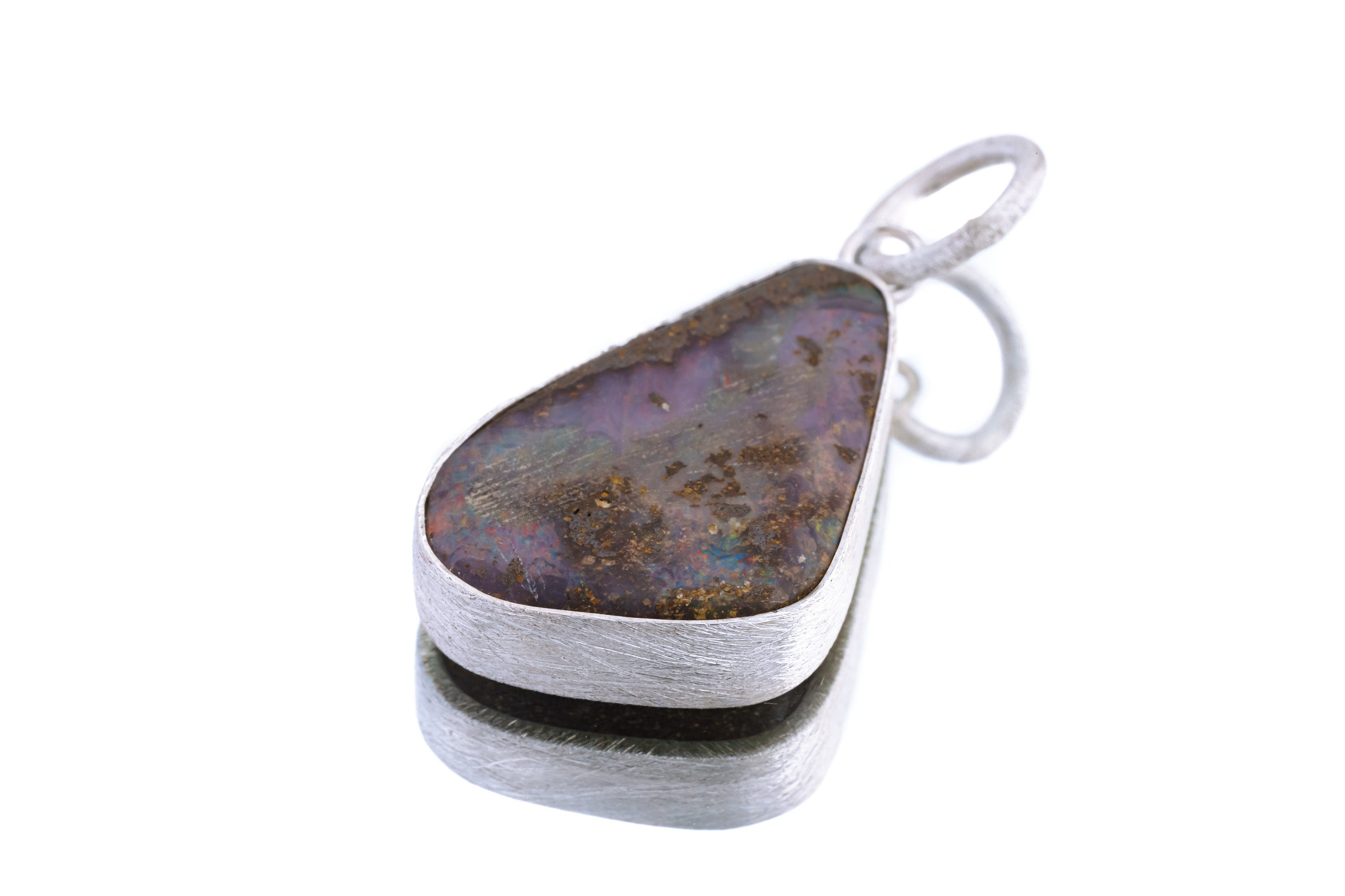 Lightning Ridge Boulder Opal pendant on white background with freeform opal face and handmade sterling silver bezel.