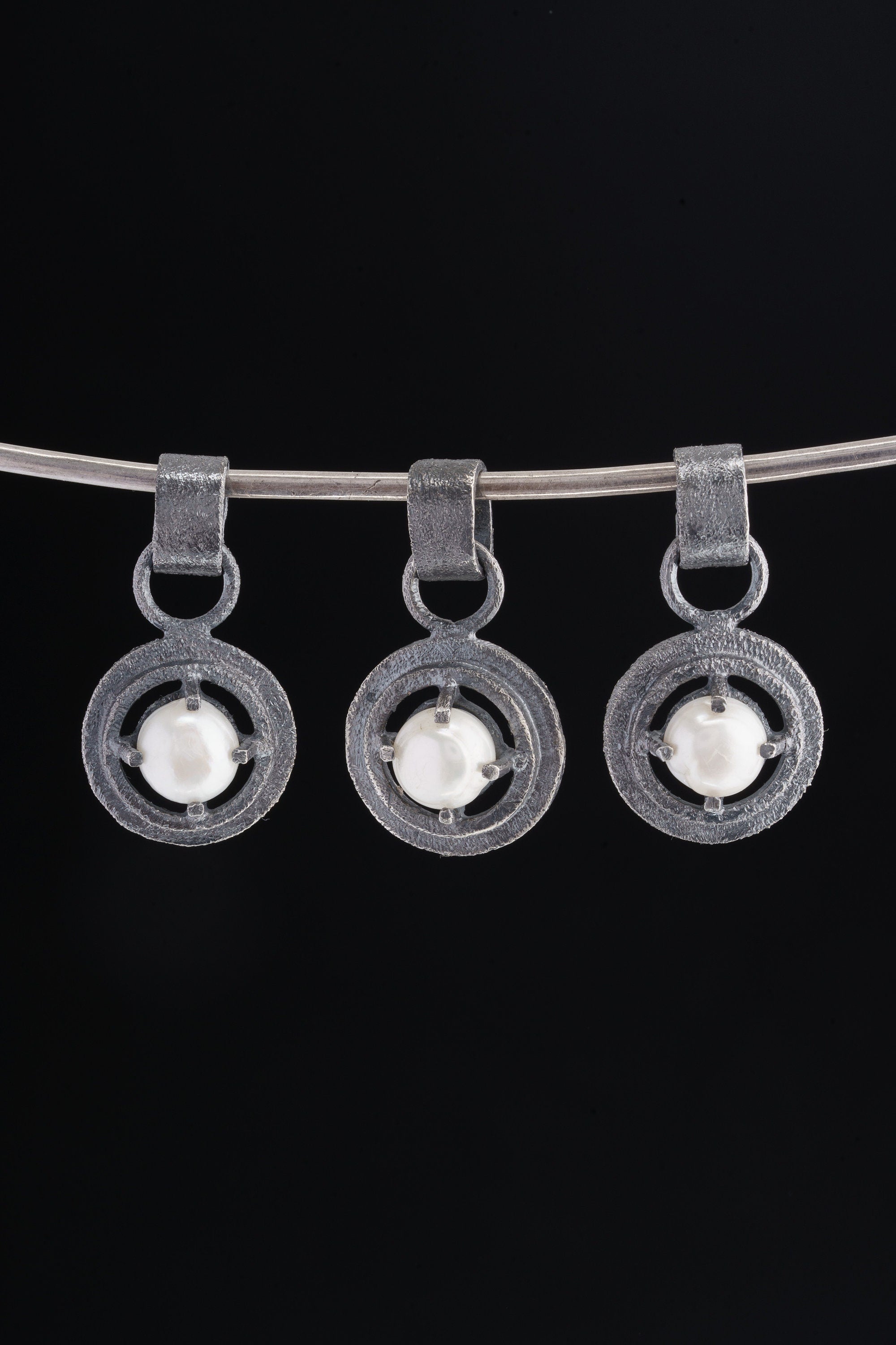 Collection of oxidized 925 sterling silver South Sea Pearl claw pendants with rugged handmade texture on a dark background.