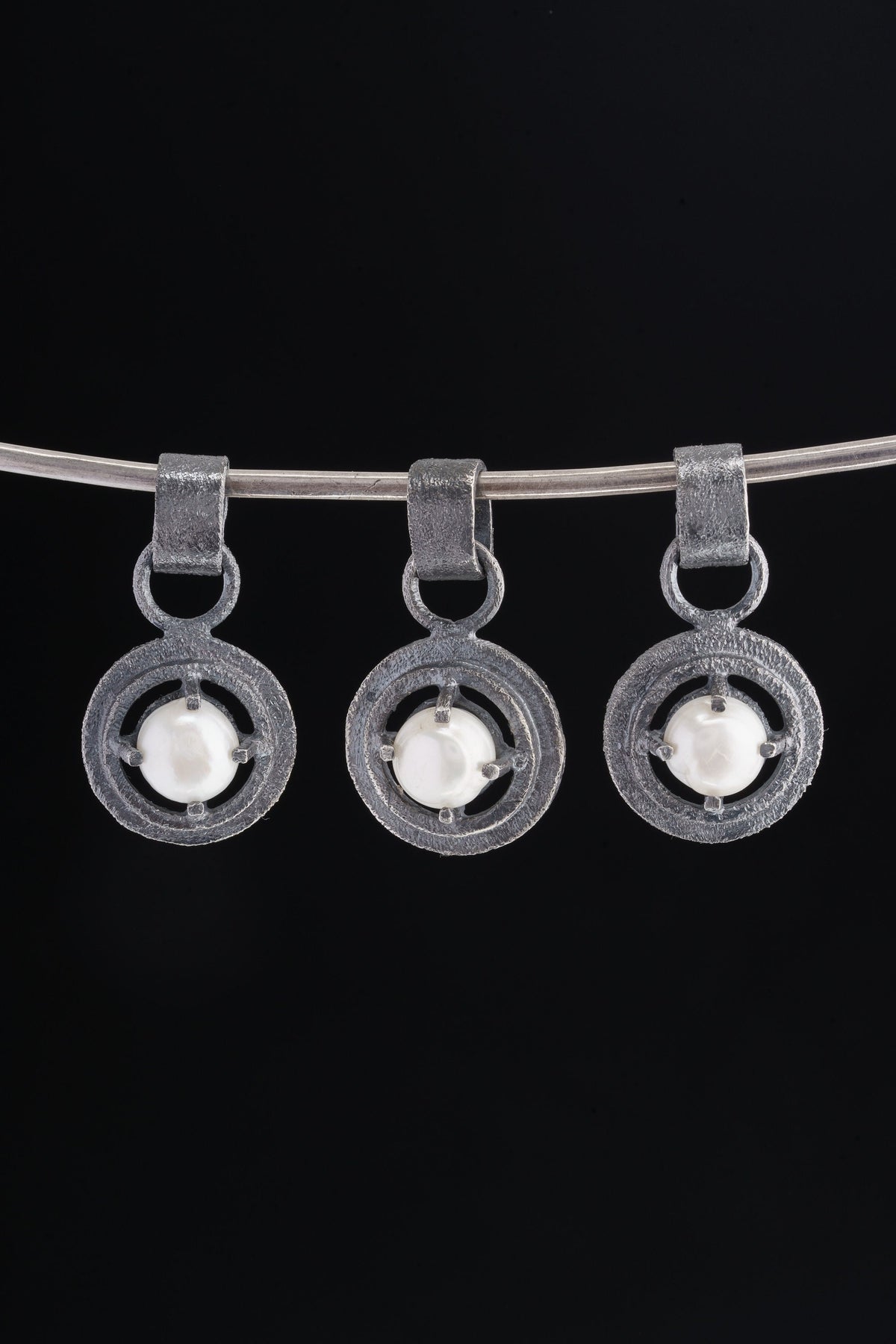Collection of oxidized 925 sterling silver South Sea Pearl claw pendants with rugged handmade texture on a dark background.