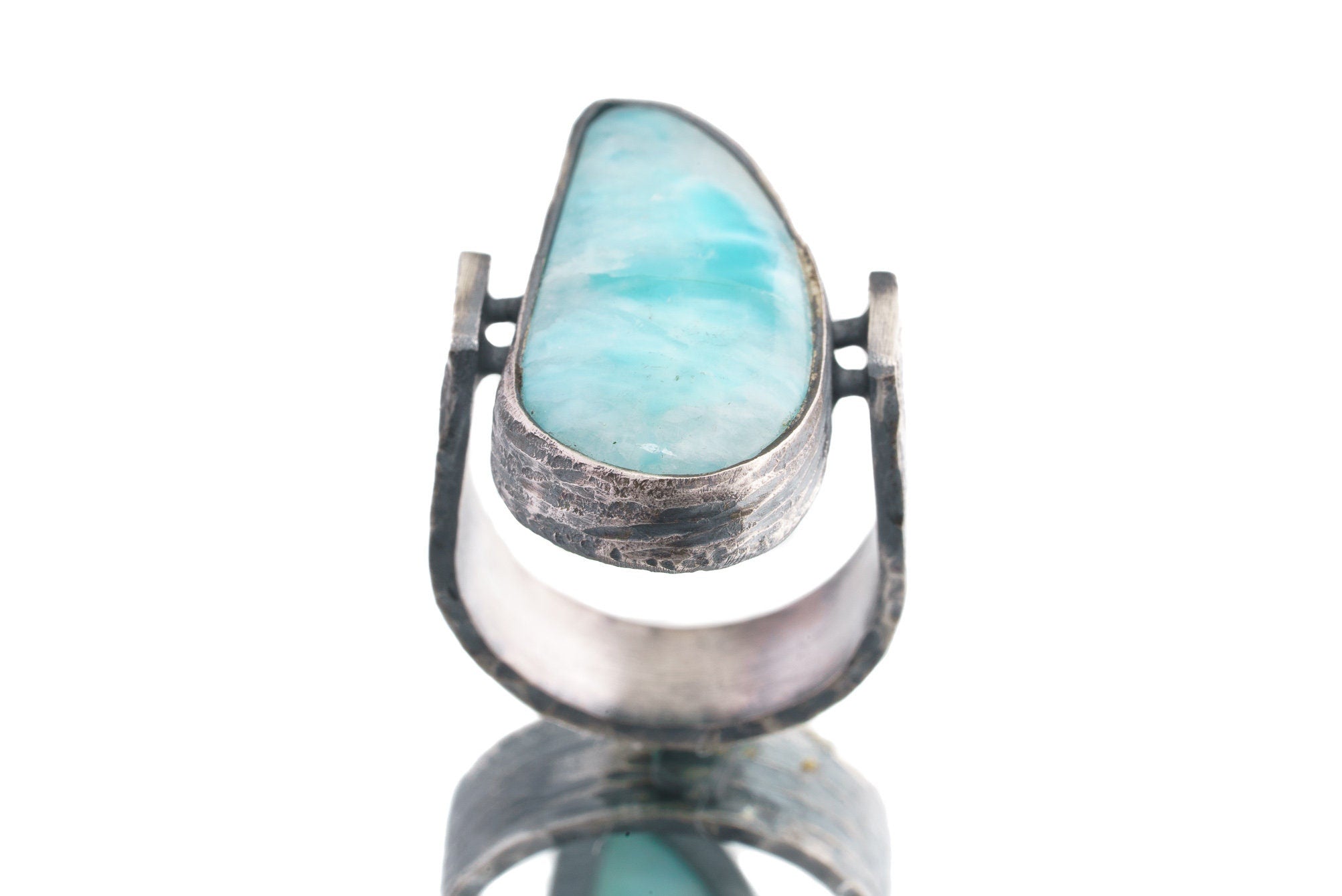 Front view of Larimar oxidized silver ring showing pale blue pectolite stone and rugged hammered band texture.