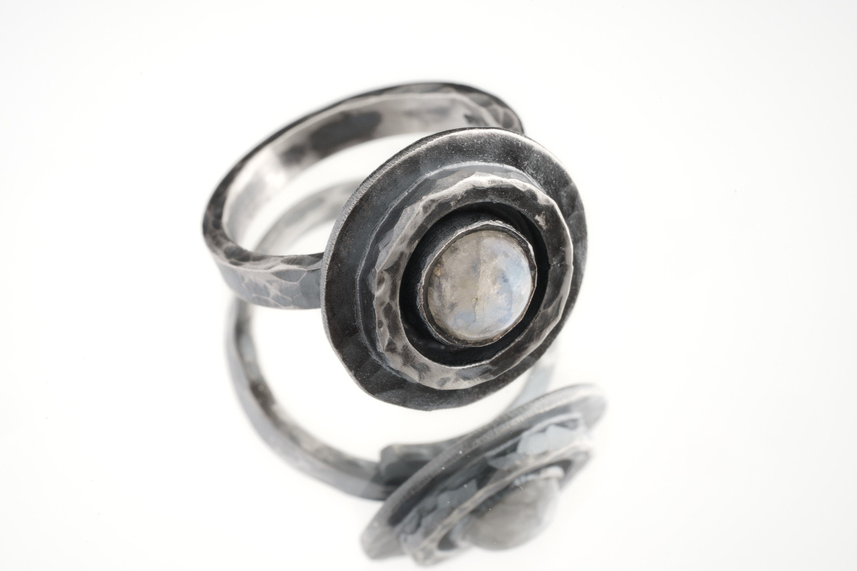 Blue Moonstone Ring shown on white background with raised textured silver face and adjustable open band.