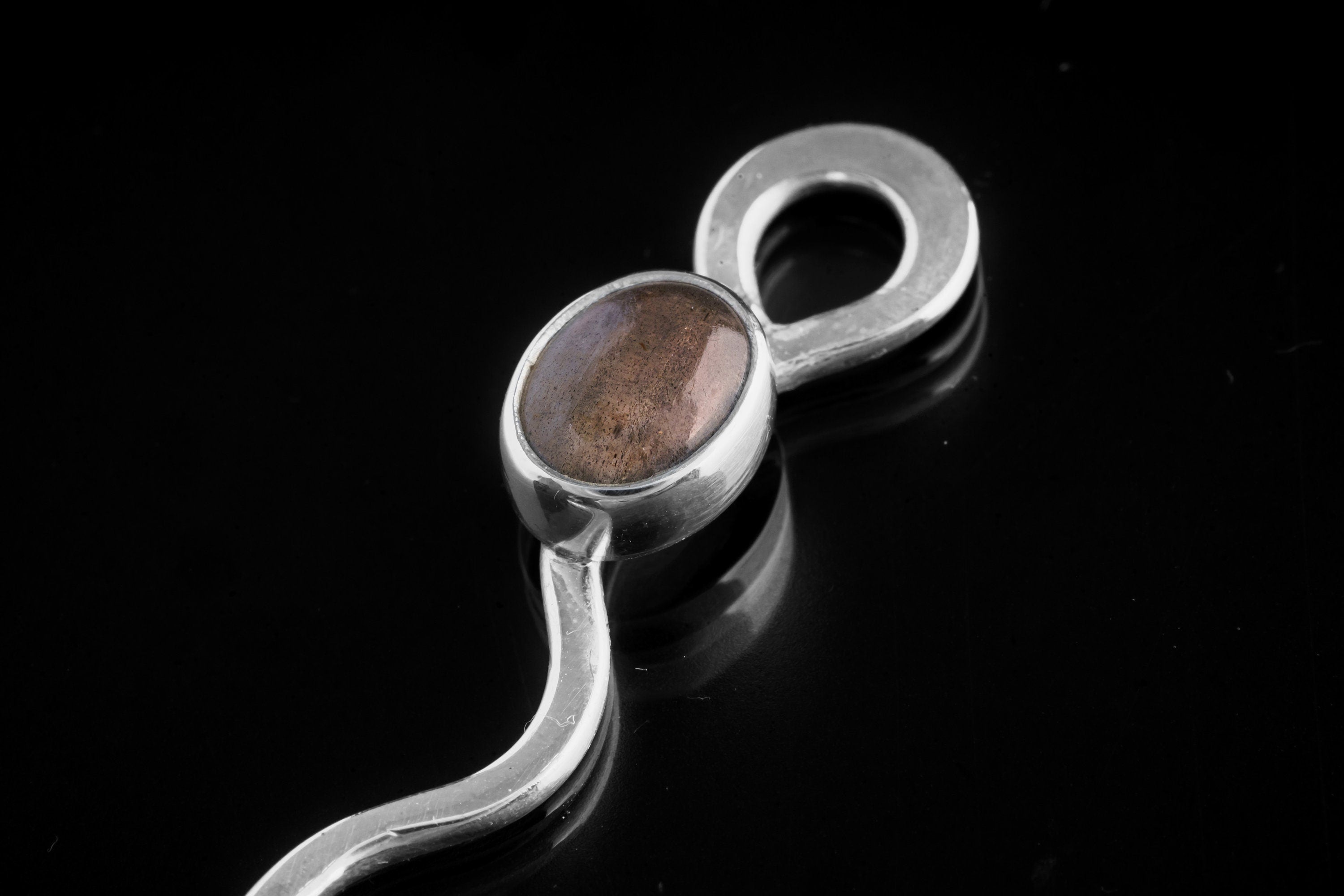 Close-up of Labradorite wavy spoon pendant showing polished sterling silver and light-shifting gemstone setting.