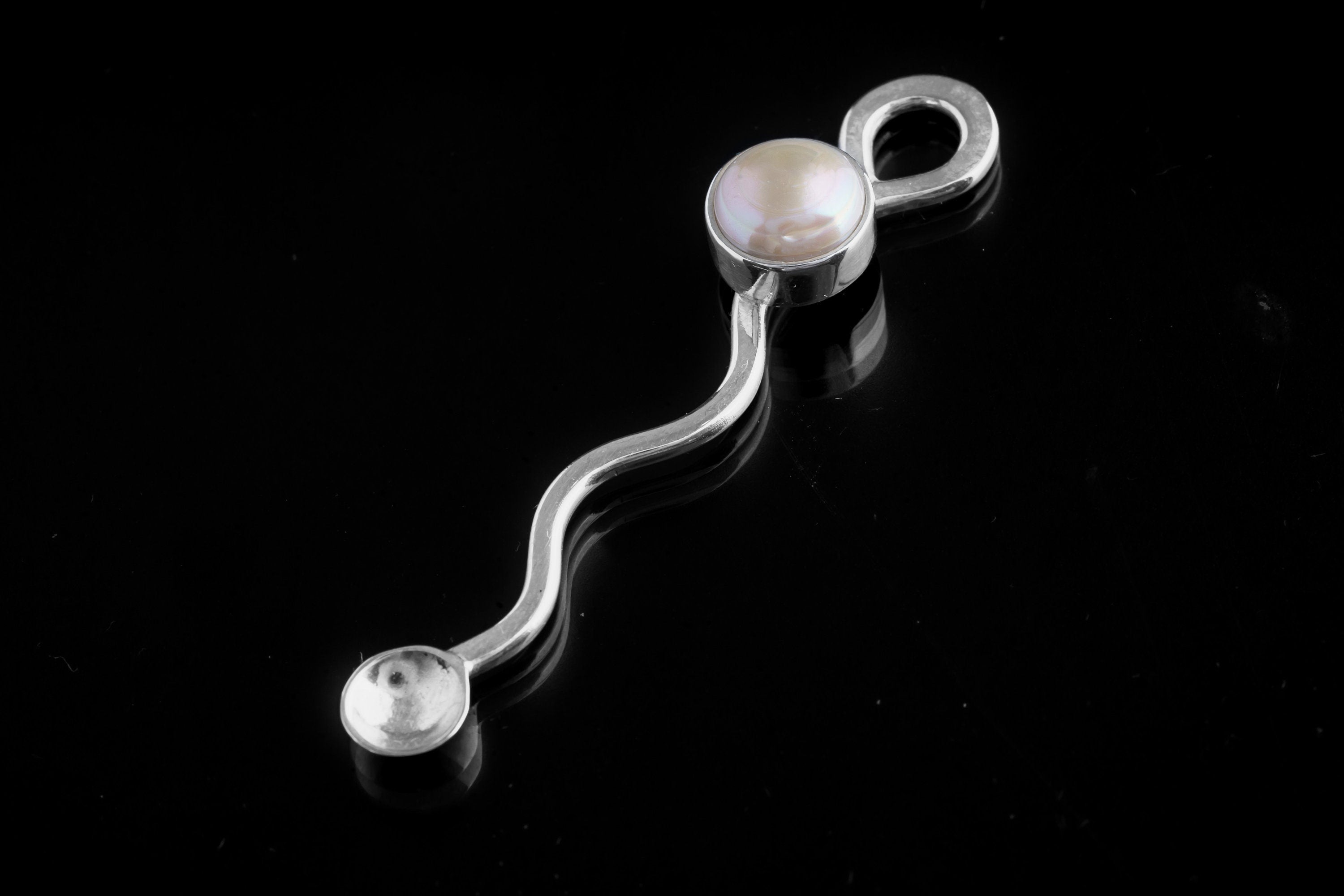South Sea Pearl spoon pendant shown on a dark background with polished 925 sterling silver wavy form.