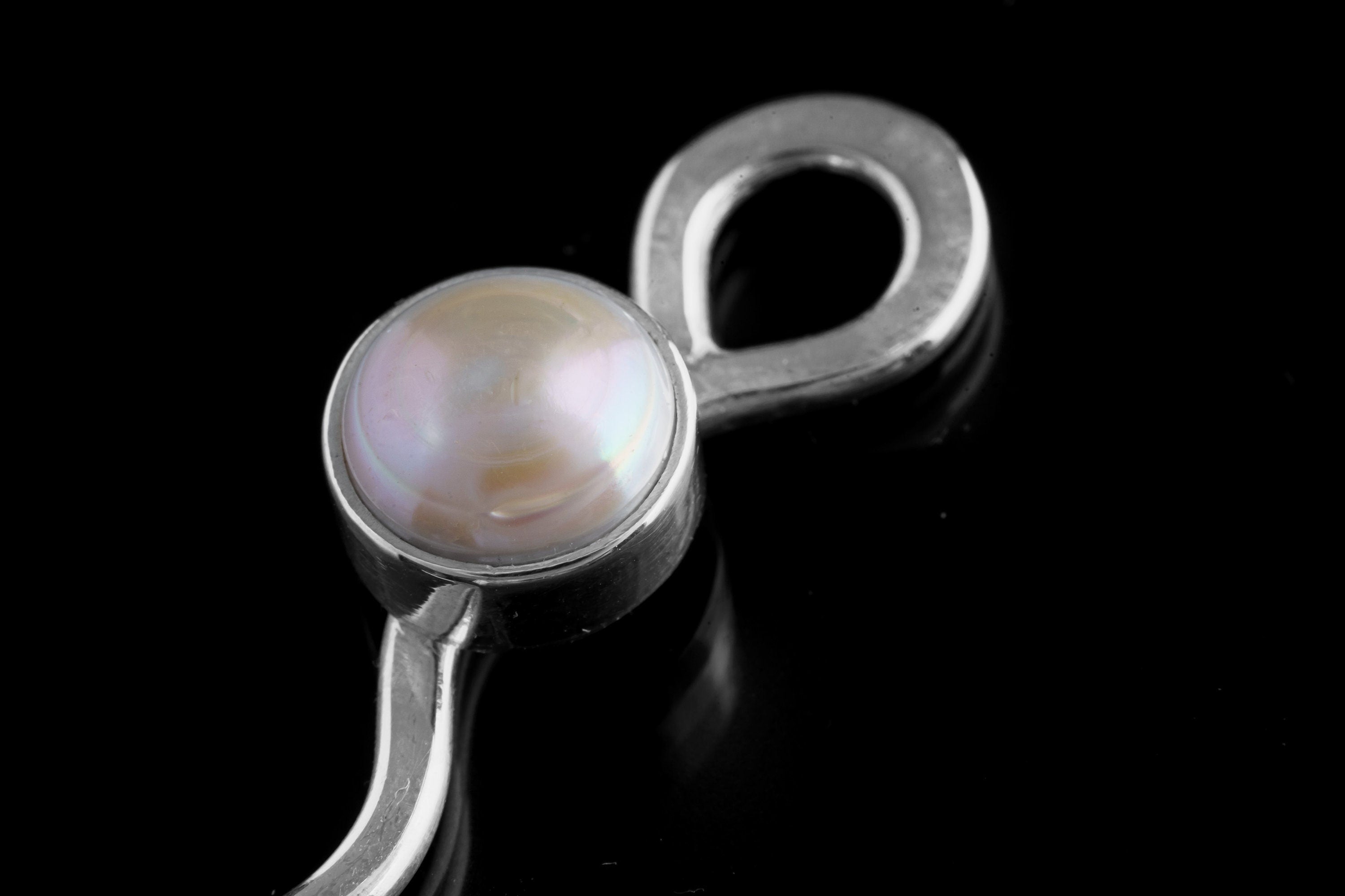 Close-up of South Sea Pearl spoon pendant showing luminous Pearl, loop bail, and polished sterling silver casting.