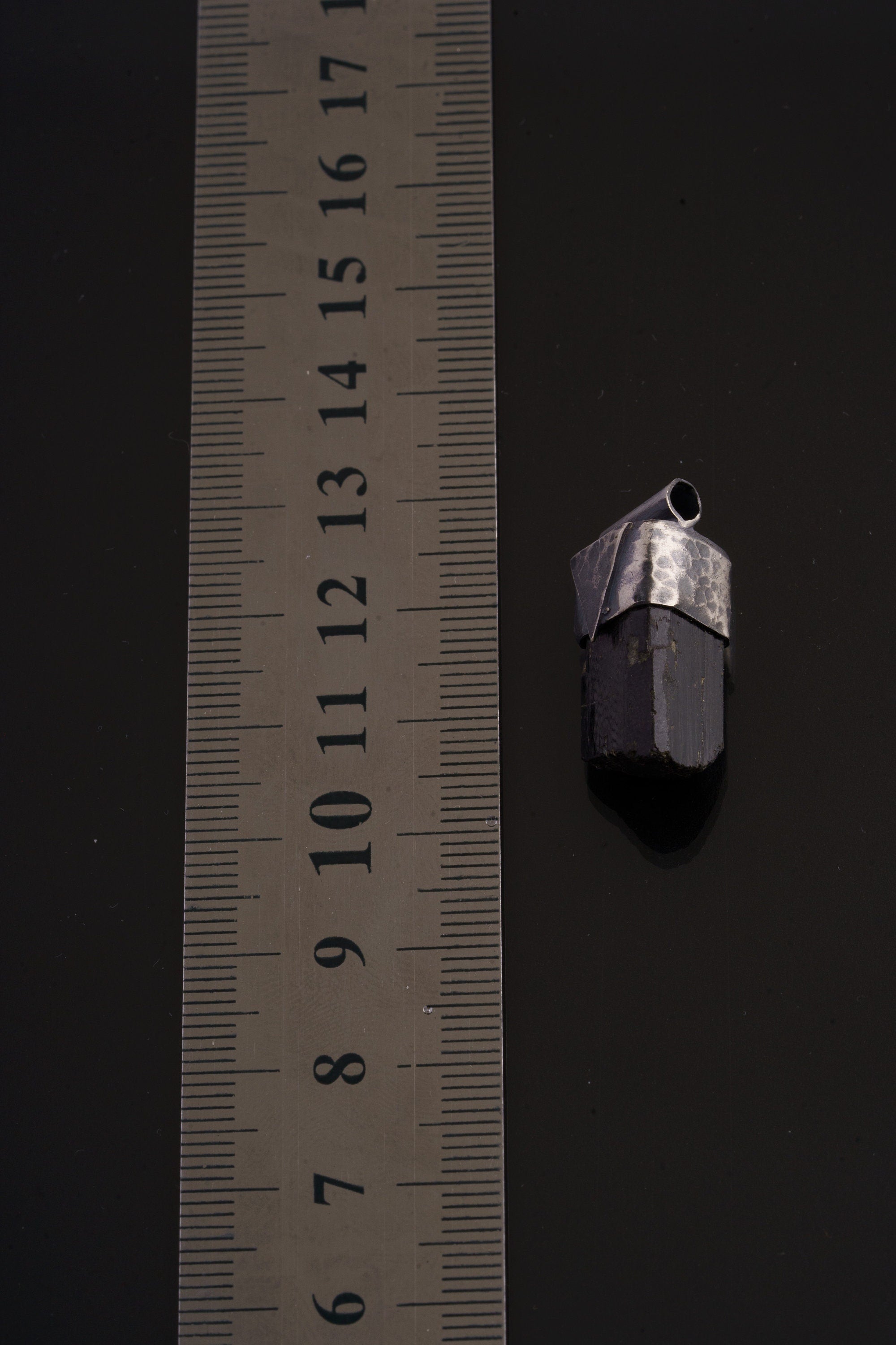 Himalayan Dravite Tourmaline Stack Pendant shown beside a ruler for scale with oxidized silver cap and dark crystal.