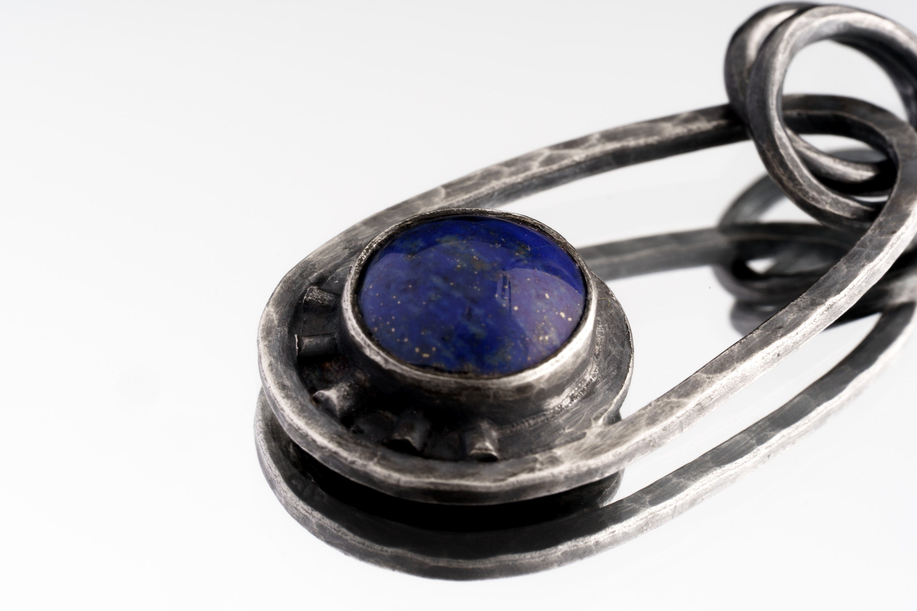 Macro detail of Lapis Lazuli cabochon in polished sterling silver, showing deep blue colour and handmade Cosmic Ray structure.