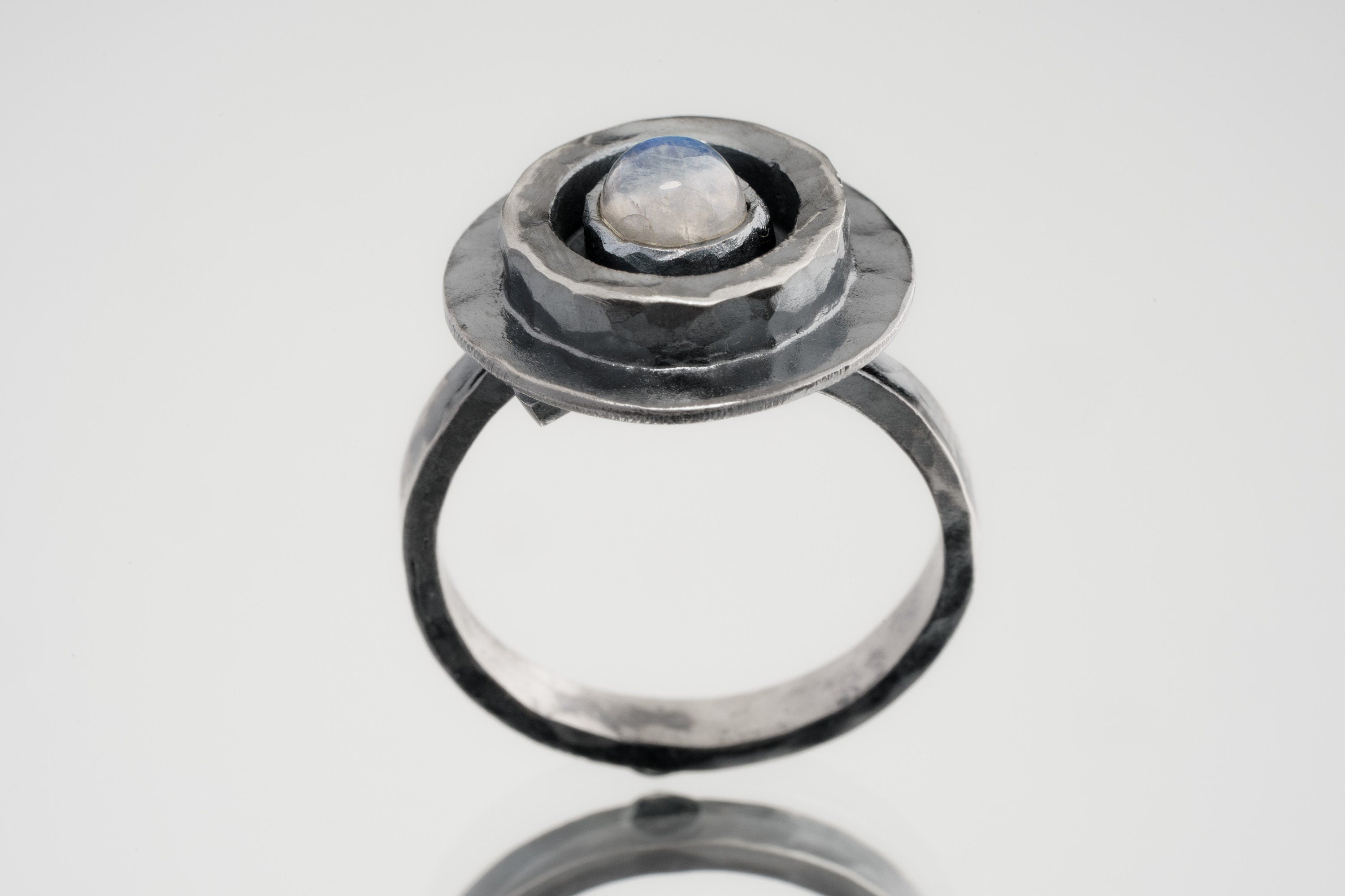 Blue Moonstone Ring shown on white background with oxidized sterling silver setting and oval blue-white cabochon.