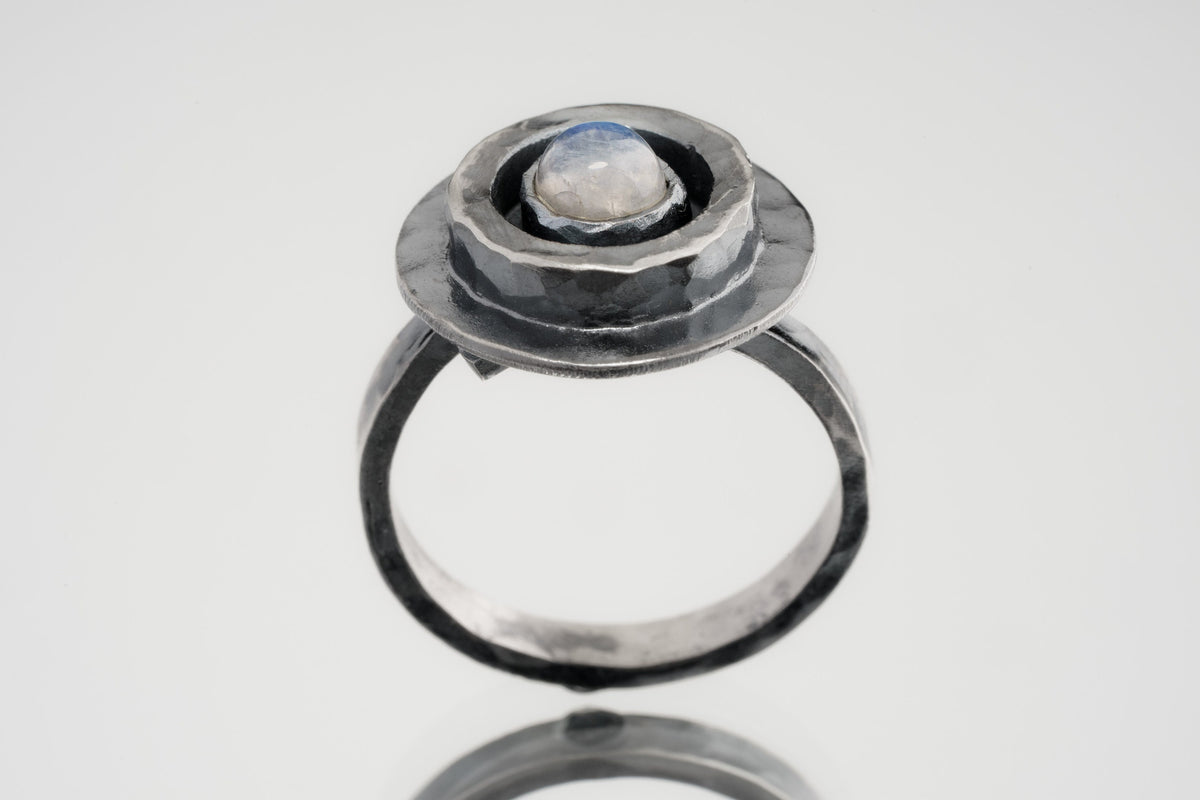 Blue Moonstone Ring shown on white background with oxidized sterling silver setting and oval blue-white cabochon.