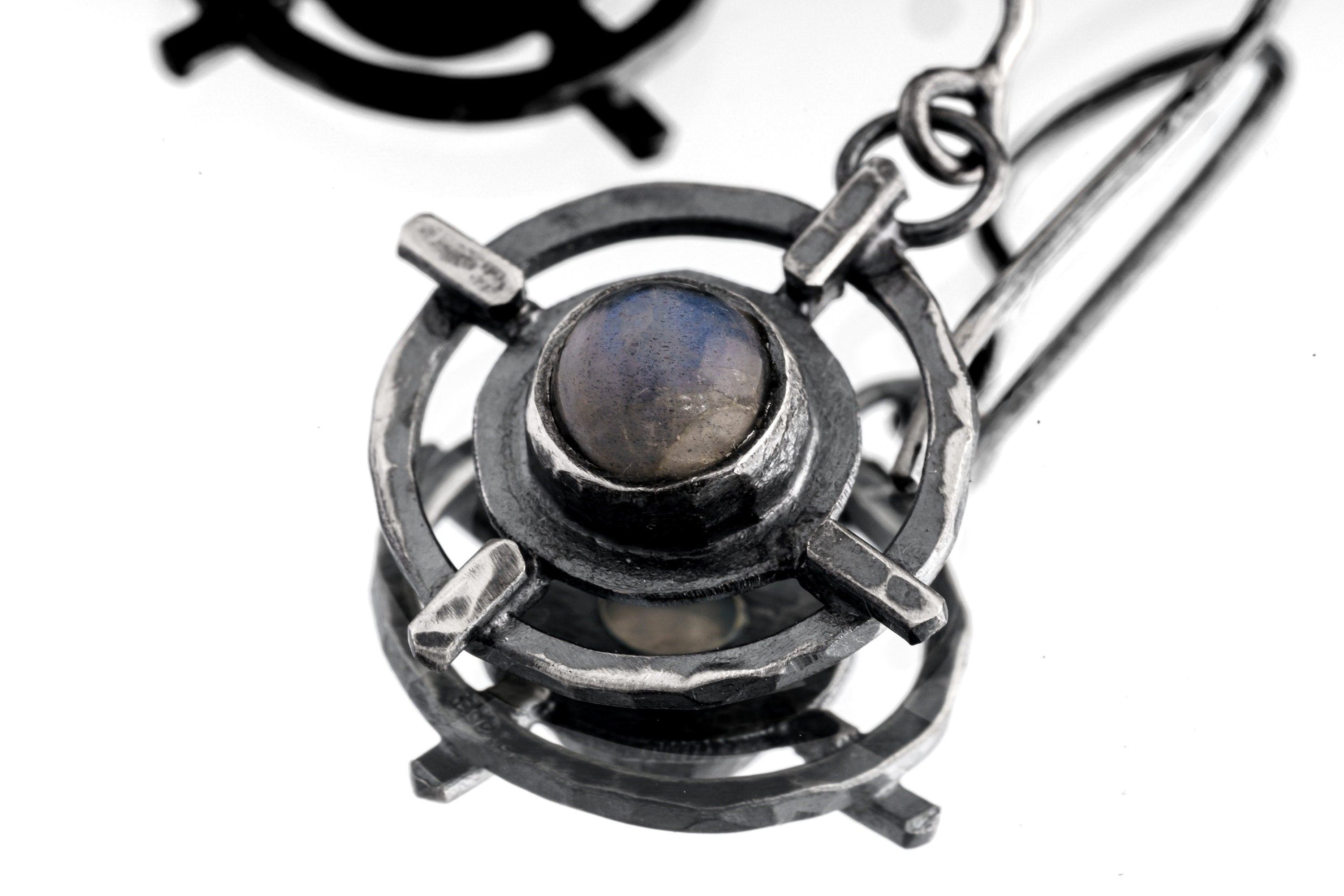 Close-up of Labradorite Circle Cross earring showing bezel-set stone, hammered silver texture, and layered talisman form.