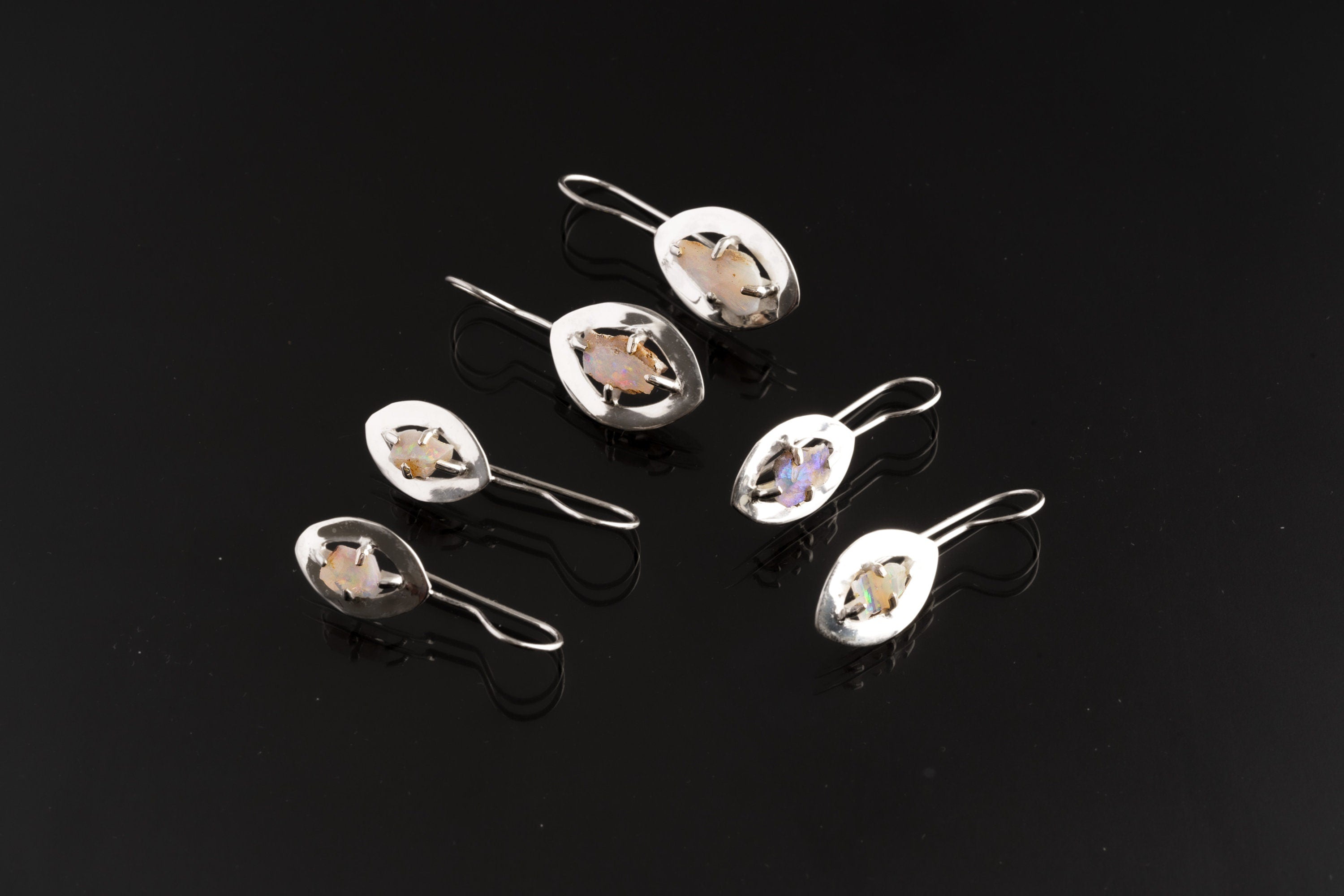 White Lightning Ridge Opal halo earrings displayed as a small collection, showing natural stone variation and silver settings.