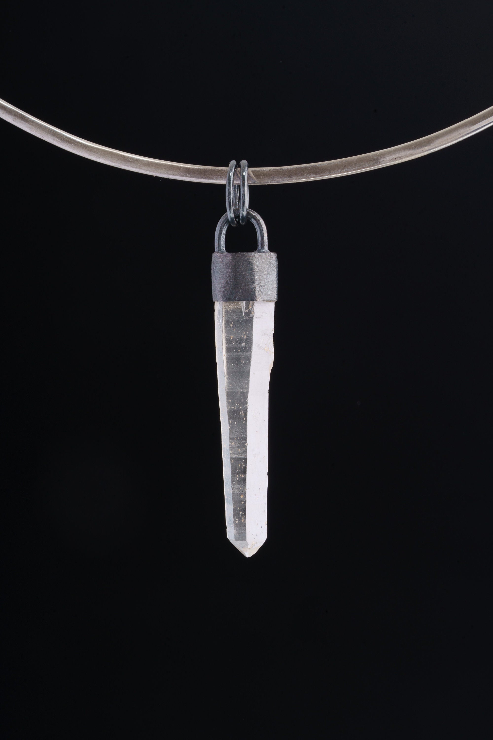 Australian Clear Quartz point pendant shown on black background with oxidized sterling silver cap and thick round coil bail.