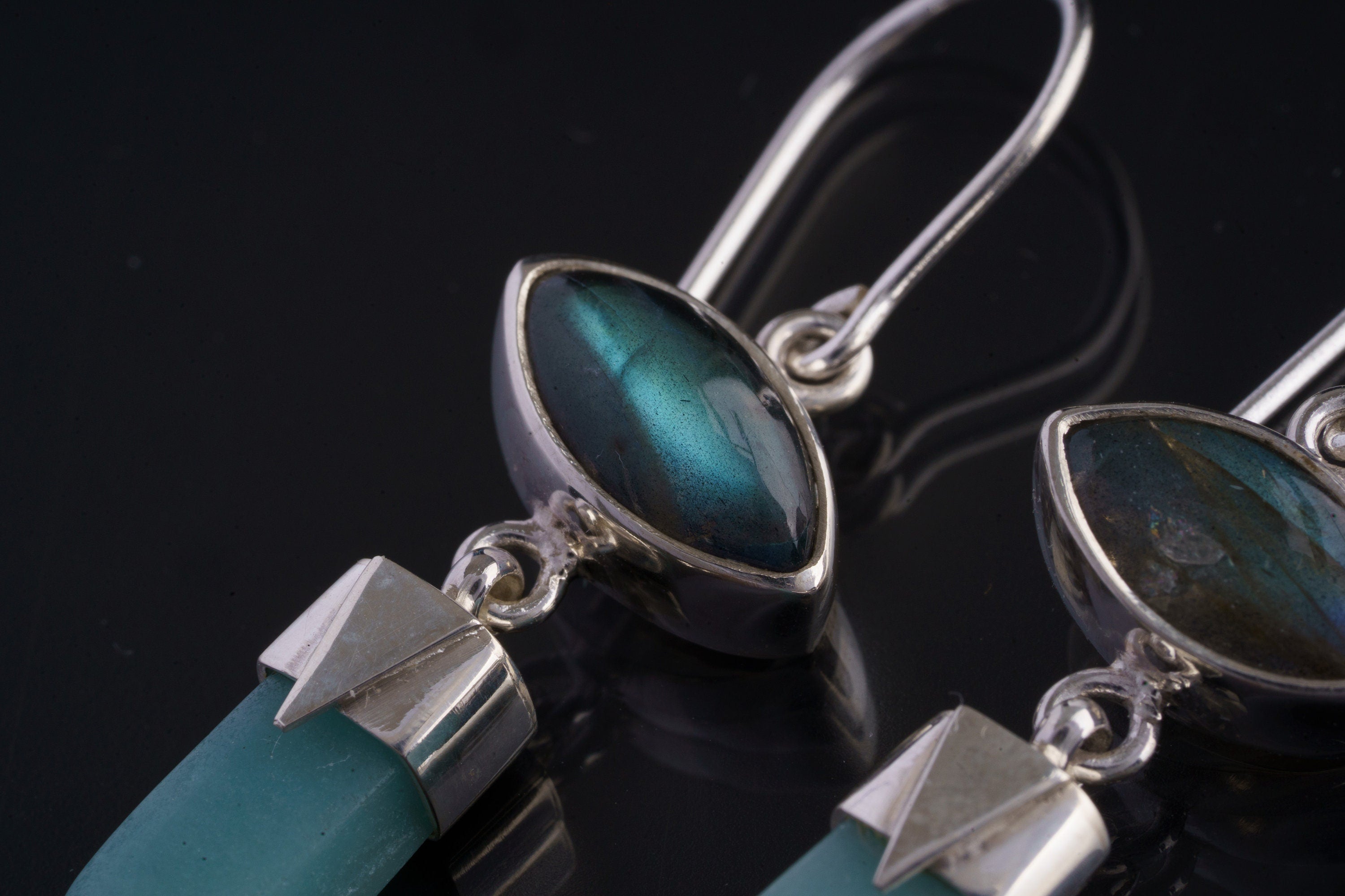 Close-up of Labradorite and Aquamarine sterling silver earrings showing eye-shaped flash and polished blue gemstone dangles.