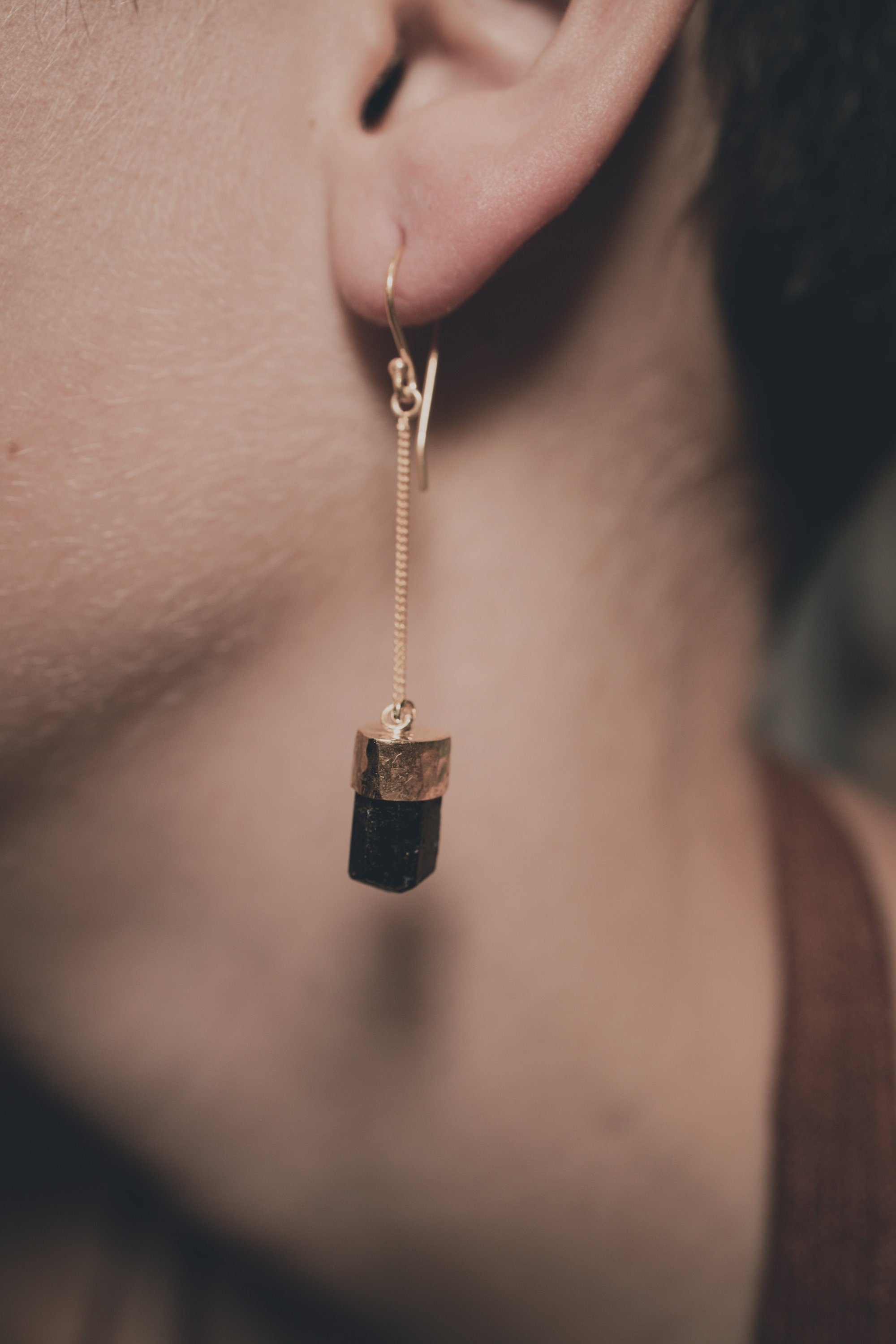 Dravite Tourmaline dangle earrings shown worn on the ear, with warm gold-plated silver and earthy translucent stones.