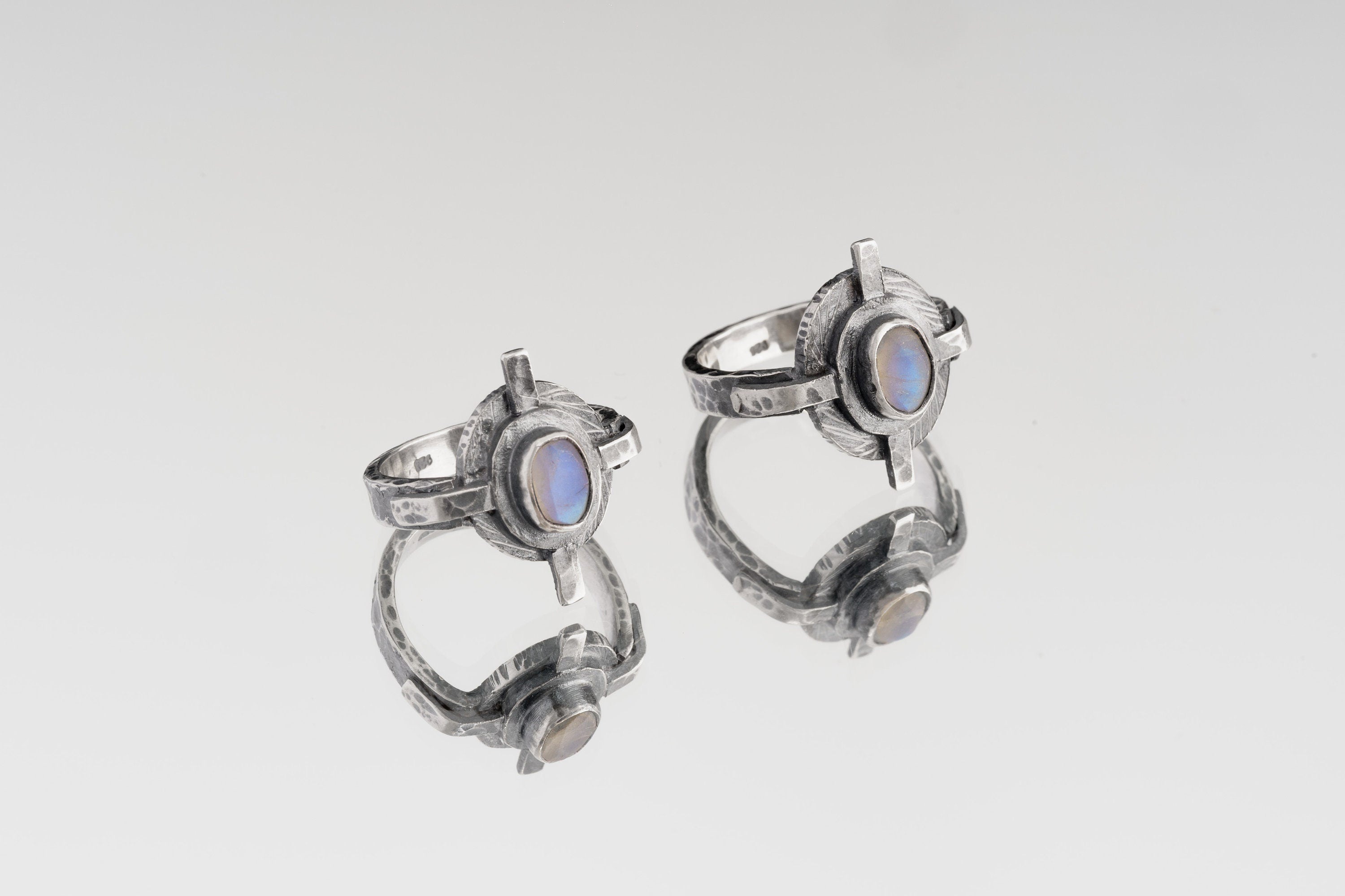 Oxidized Blue Moonstone Compass Ring shown on white background with hammered sterling silver face and oval Moonstone centre.