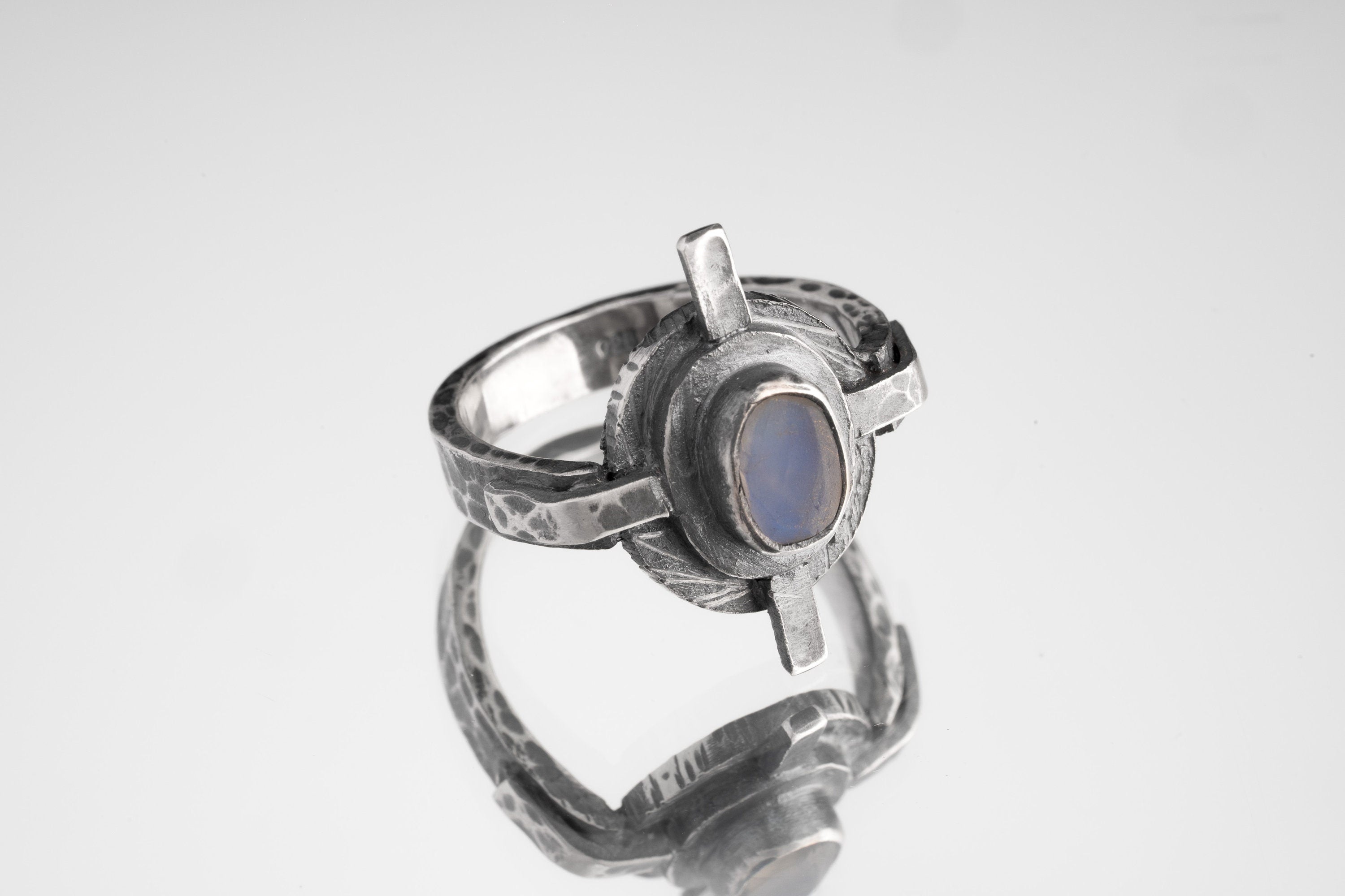 Oxidized Blue Moonstone Compass Ring shown on white background with four directional silver points and hammered texture.