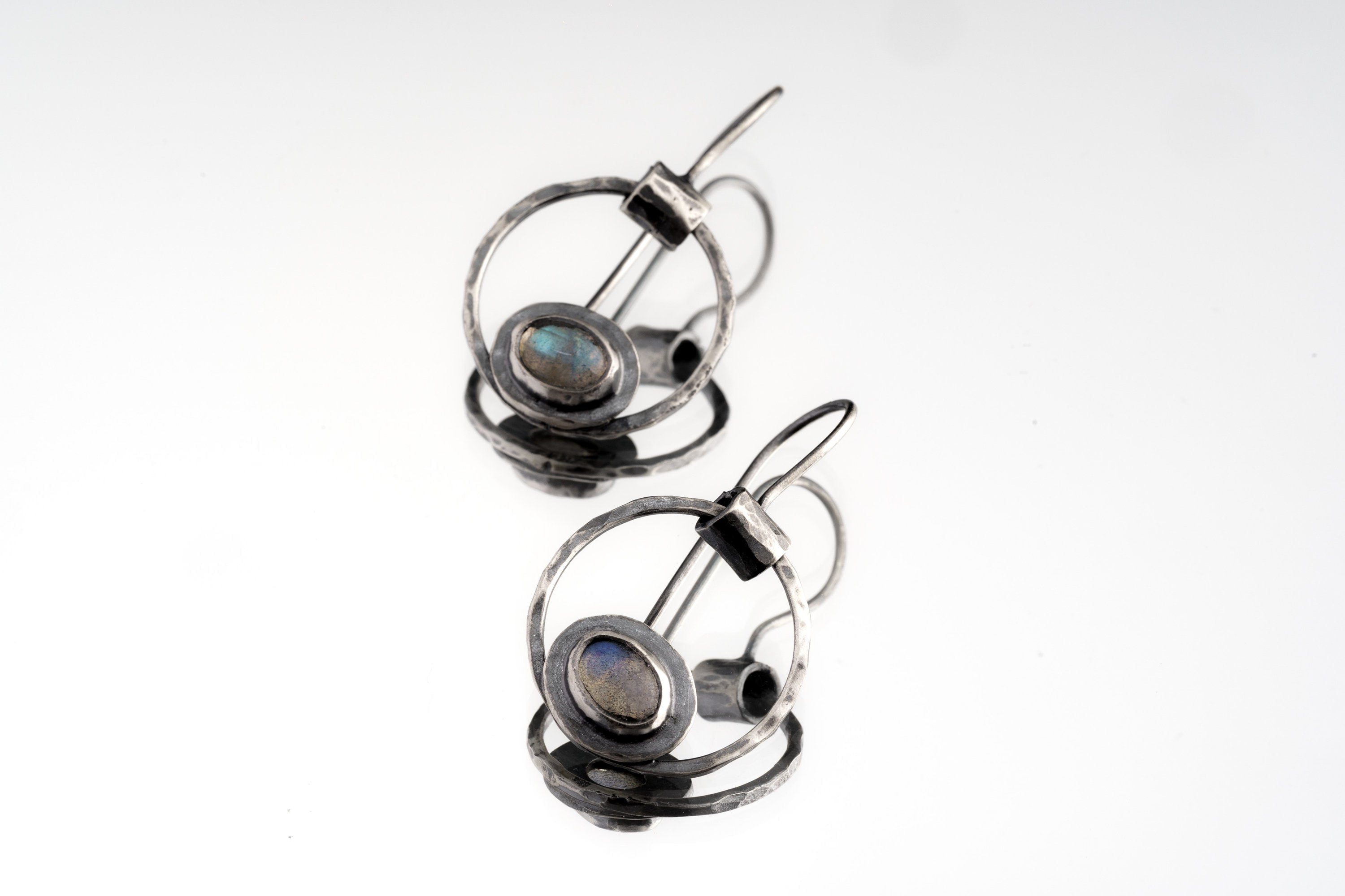Old World Labradorite Cat Eye earrings in hammered 925 sterling silver shown worn on the ear with circular dangle form.
