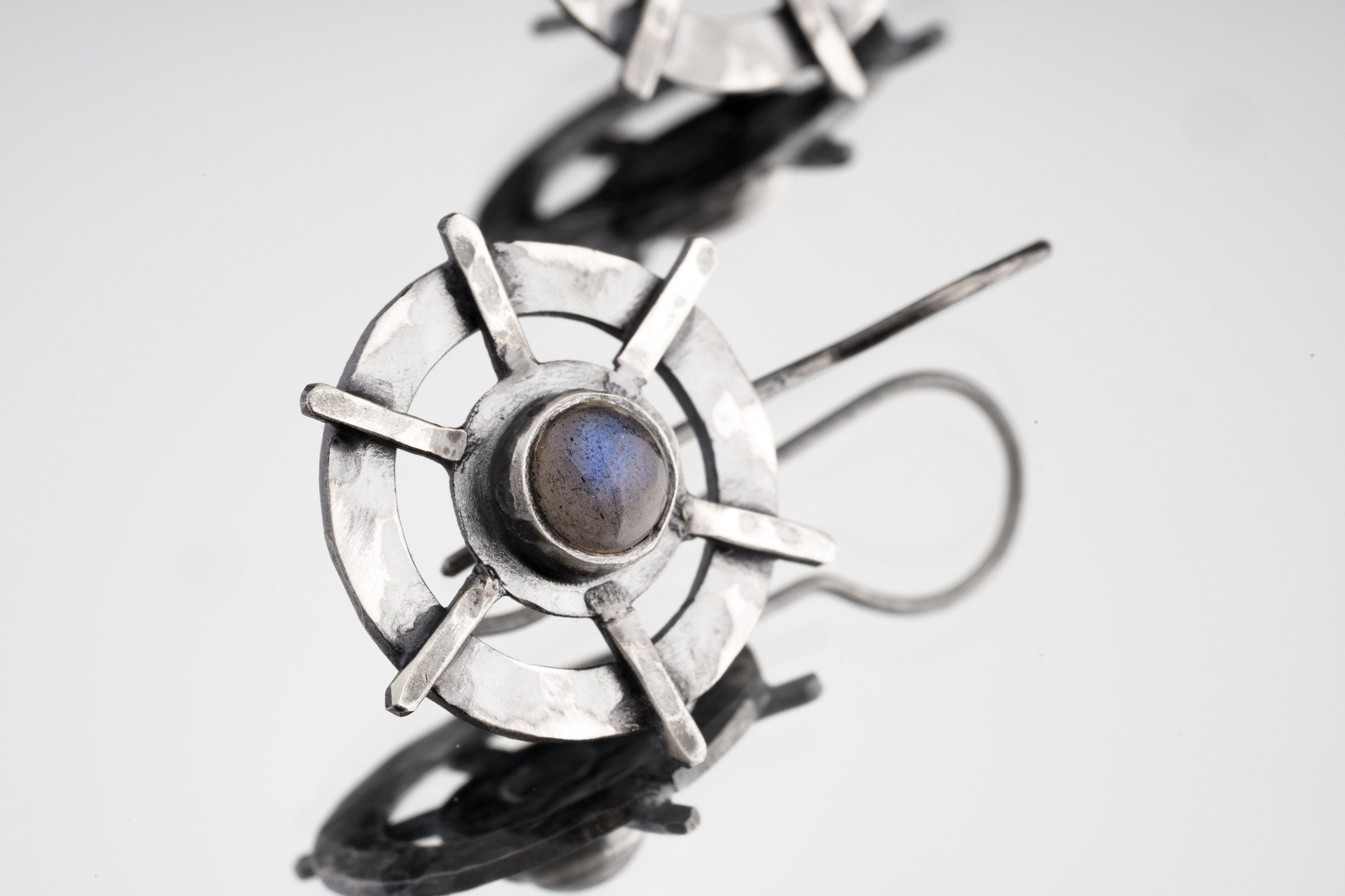 Close-up of Labradorite Circle Cross earrings showing hammered silver layers, round forms, and bezel-set flashing stones.