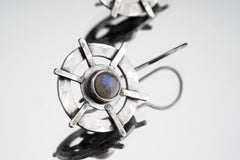 Close-up of Labradorite Circle Cross earrings showing hammered silver layers, round forms, and bezel-set flashing stones.