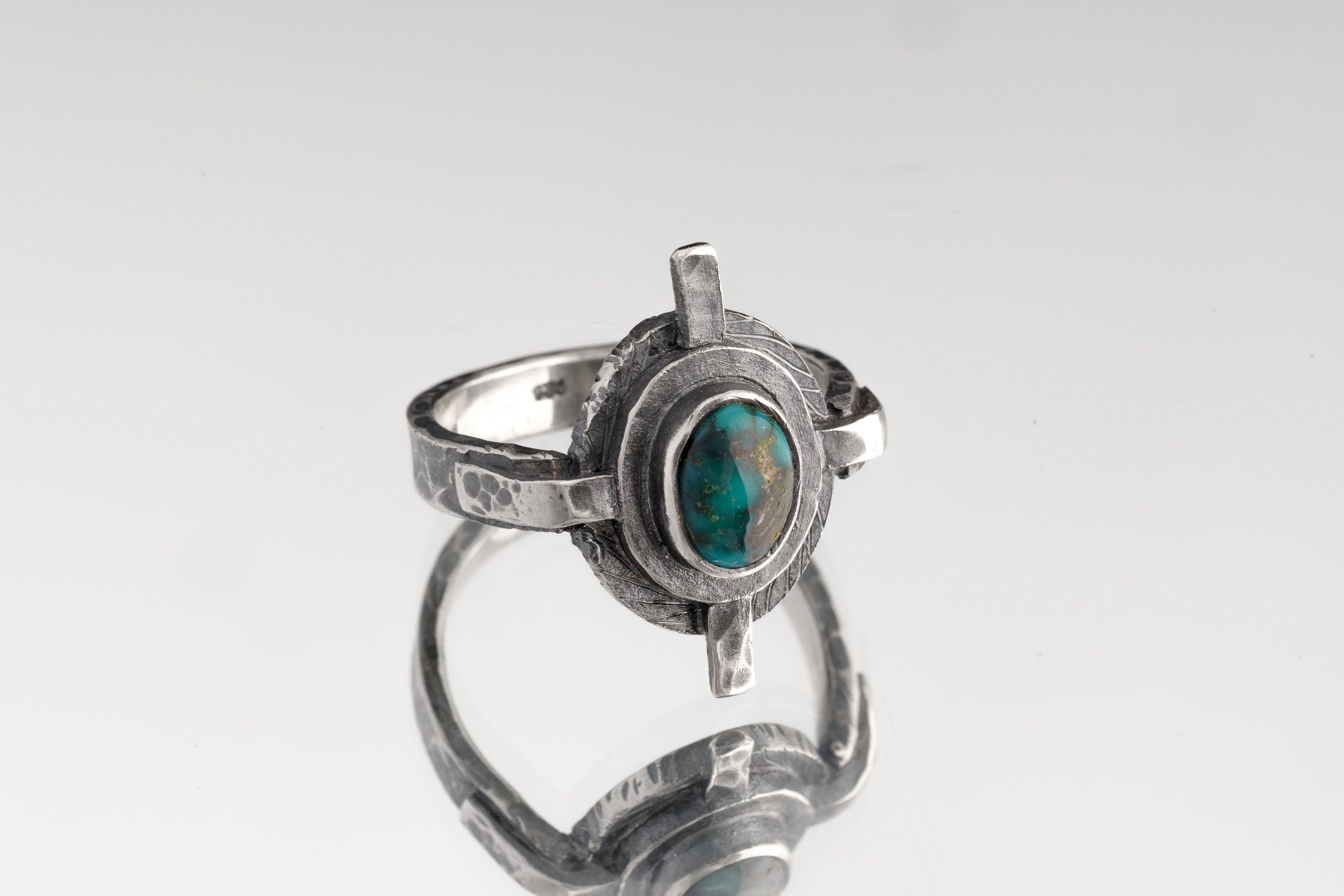 Himalayan Turquoise Compass Ring shown from the side with sculptural silver band and raised Turquoise setting.