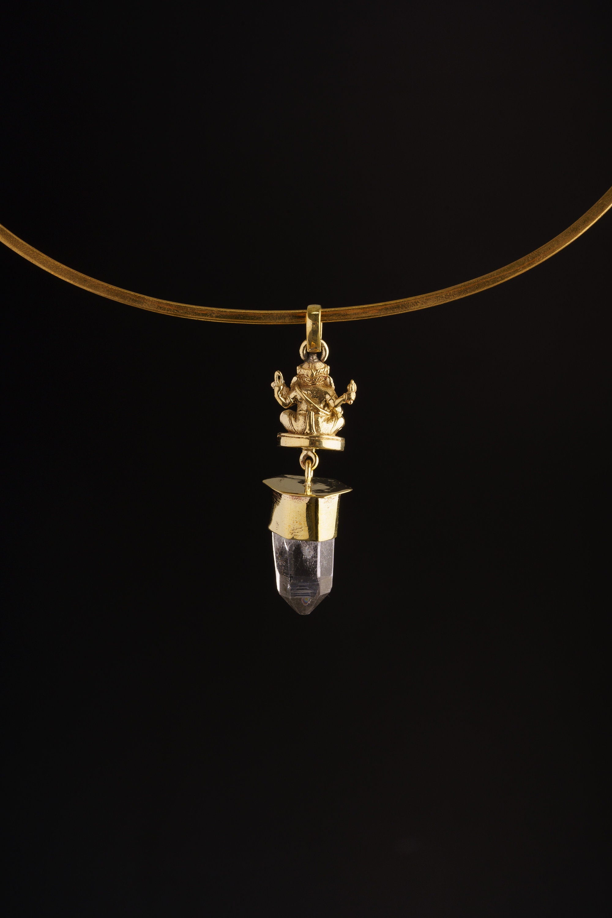 Meditating Ganesha Clear Quartz pendant shown worn on a black background as a lightweight golden brass spiritual charm.
