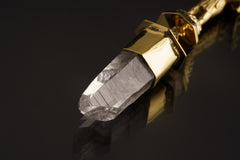 Close-up of Himalayan Clear Quartz crystal suspended beneath a high-polish brass Ganesha talisman pendant.