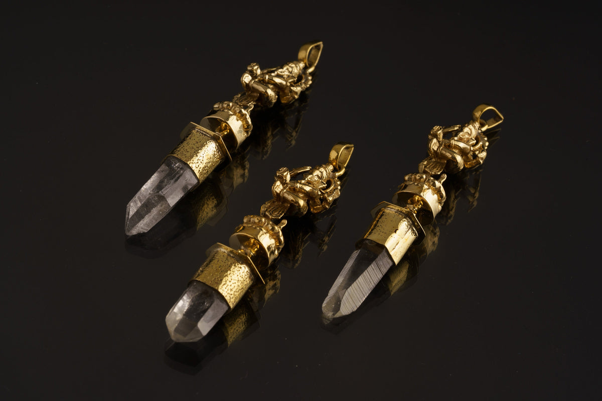 Dancing Ganesha Clear Quartz talisman pendant shown on a dark background with hammered brass figure and Himalayan Quartz crystal.
