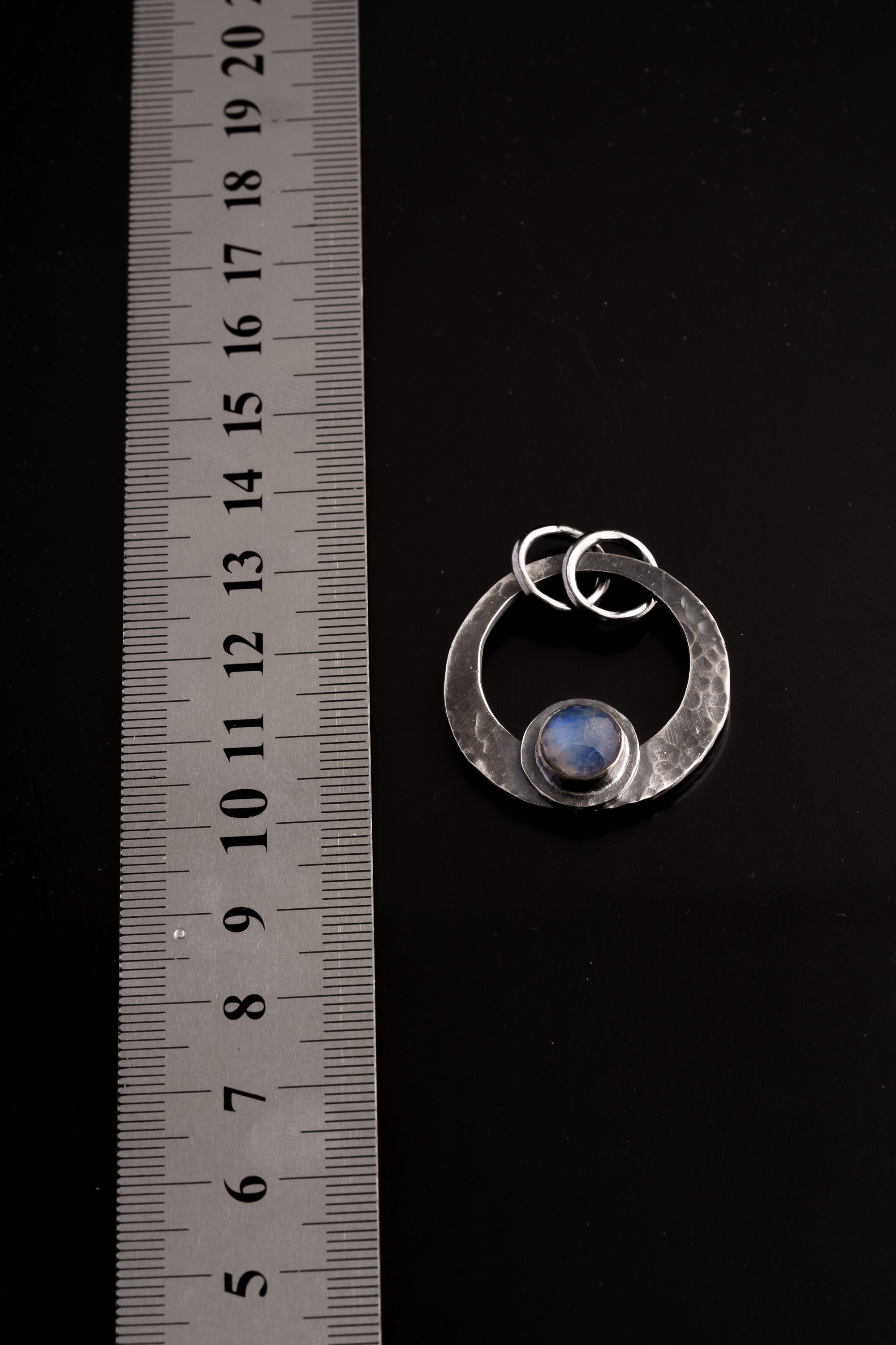Blue Moonstone crescent pendant shown beside a ruler for scale, measuring approximately 3.5 to 4 cm including bail.