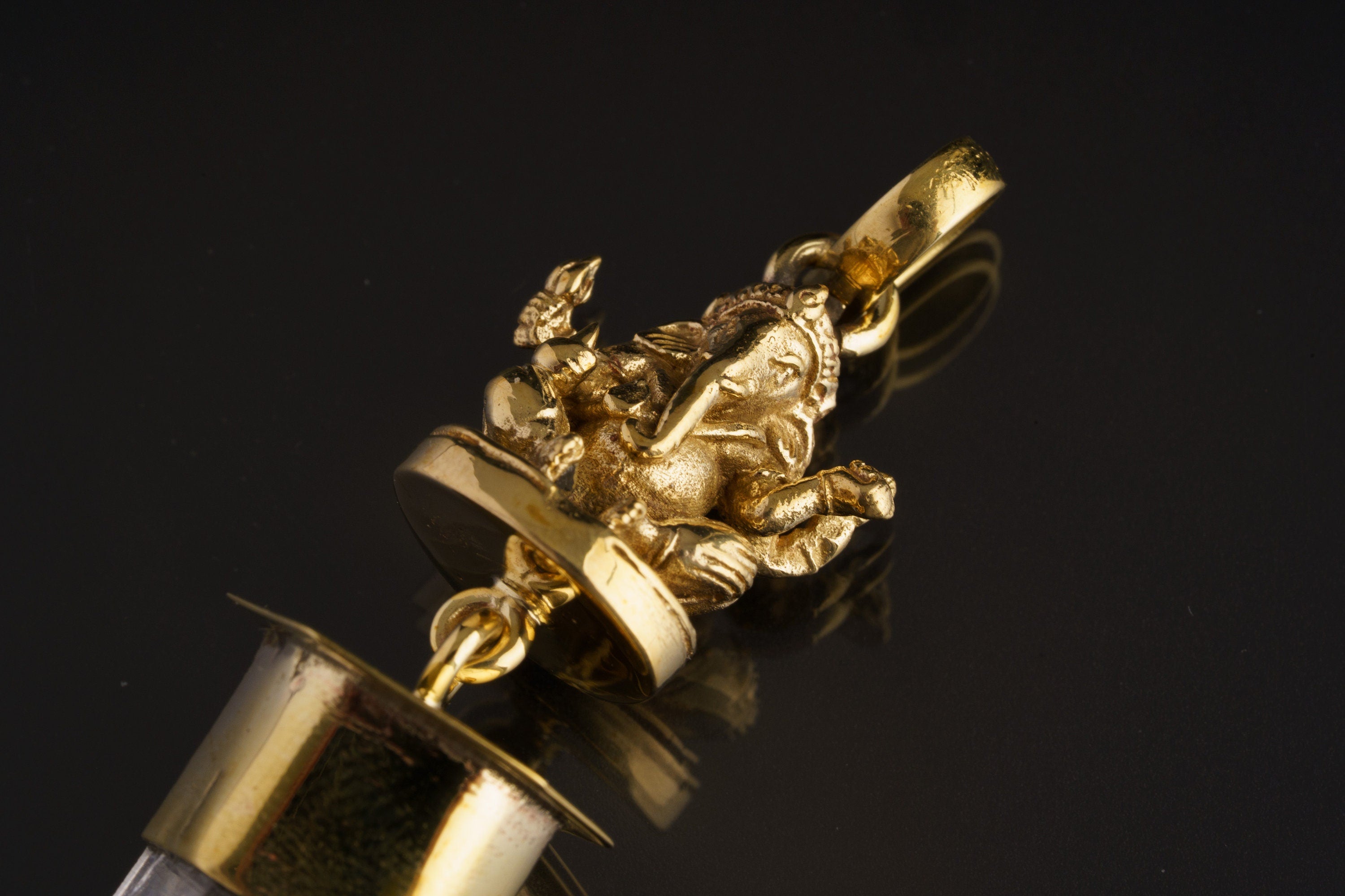 Close-up of brass meditating Ganesha figure above Himalayan Clear Quartz in a handmade spiritual talisman pendant.
