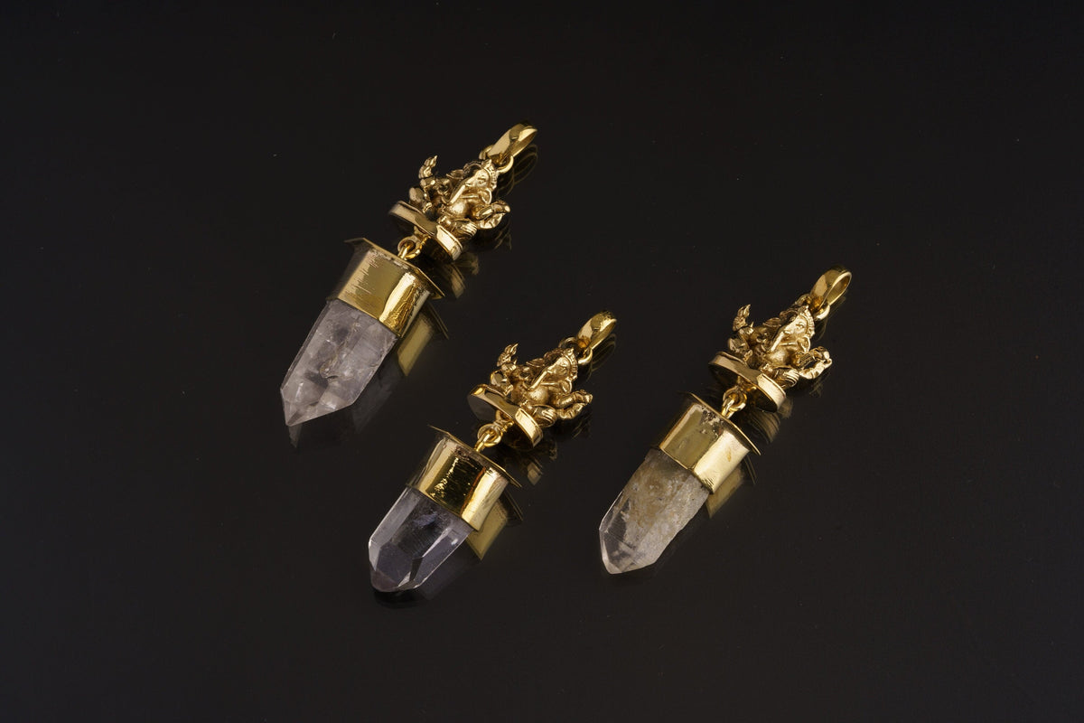 Meditating Ganesha Clear Quartz talisman pendant shown on black background with golden brass figure and crystal point.