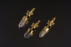 Meditating Ganesha Clear Quartz talisman pendant shown on black background with golden brass figure and crystal point.