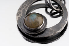 Close-up of Rainbow Labradorite set in a hammered oxidized sterling silver crescent moon pendant.