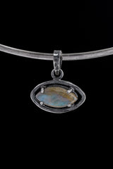 Small oxidized sterling silver Labradorite pendant shown worn on a necklace, with subtle blue-green flash and claw-set detail.