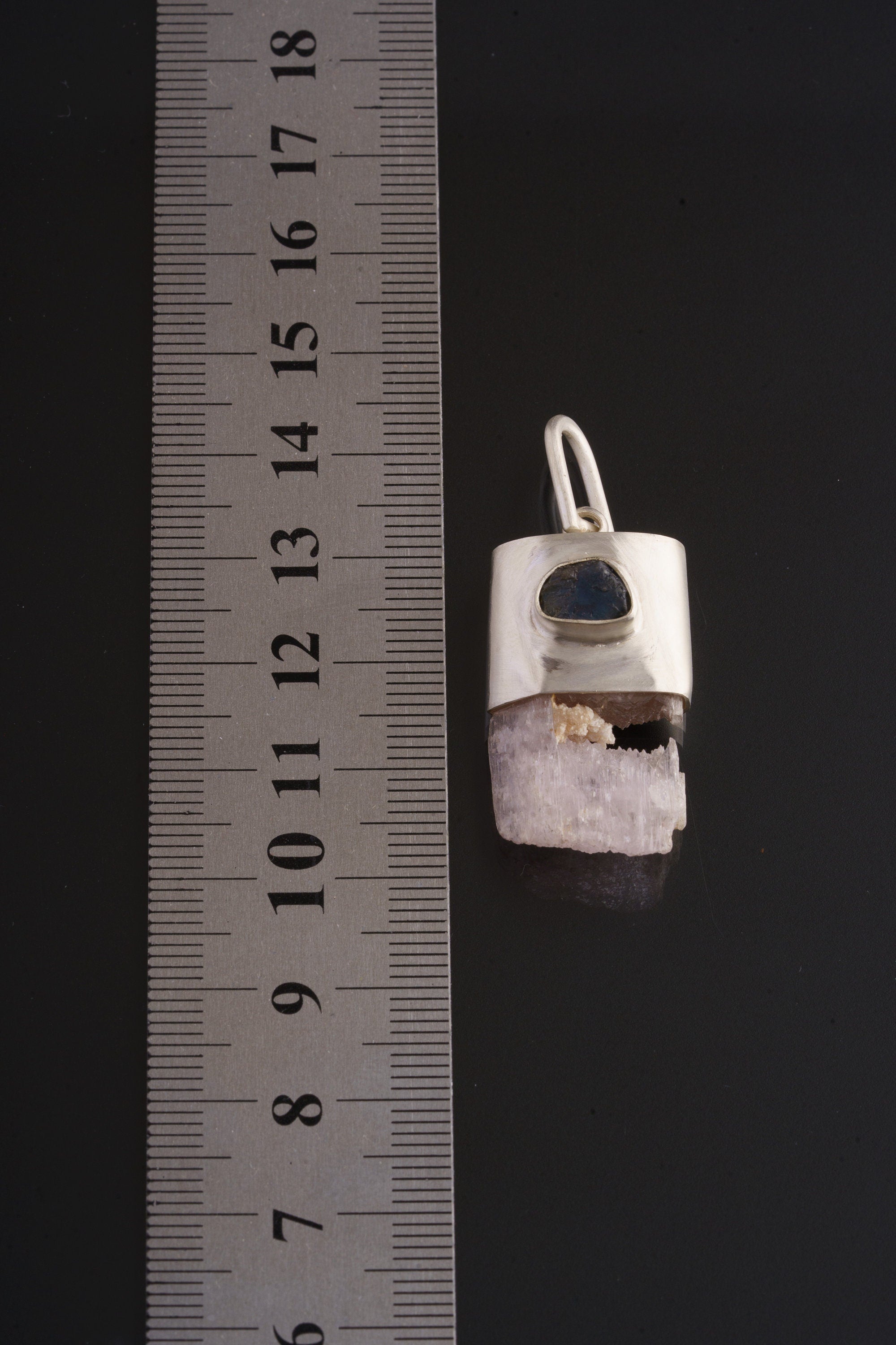 Pink Kunzite Sapphire pendant shown beside a ruler for scale, with raw crystal termination and sterling silver cap.