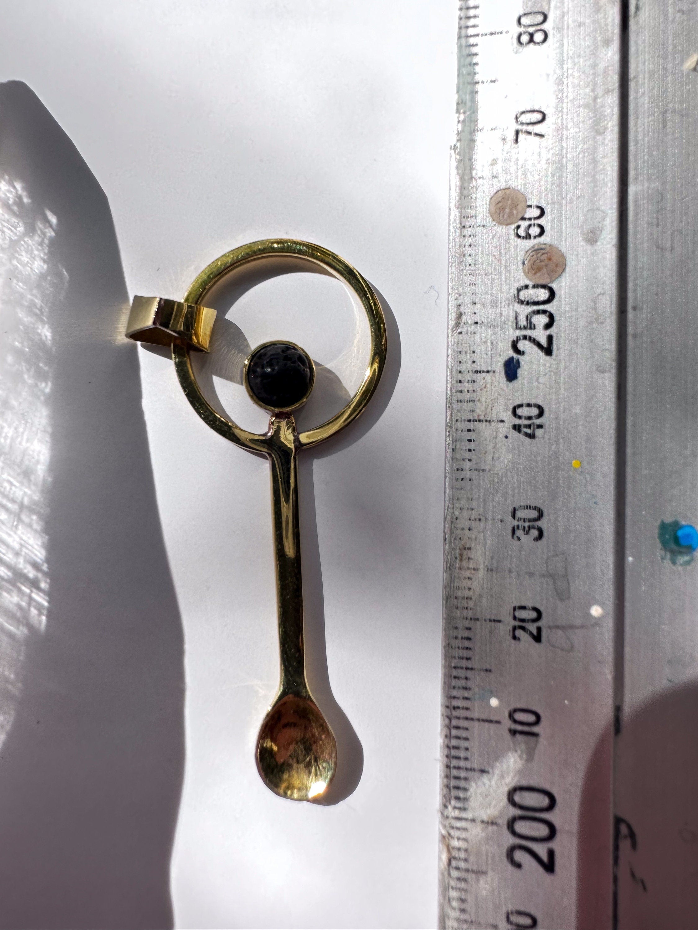 Mount Agung volcanic stone ritual spoon shown beside a ruler for scale with gold-plated brass spoon form.